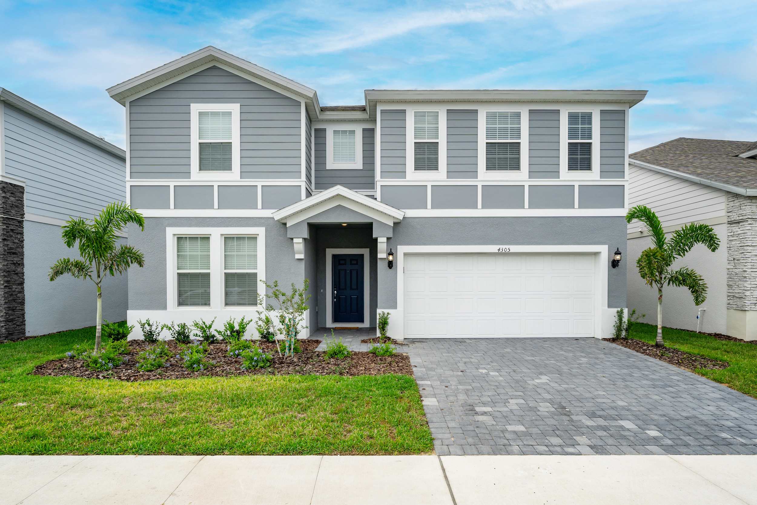 Elegant two-story villa with a spacious driveway and charming landscaping, perfect for a luxurious getaway.