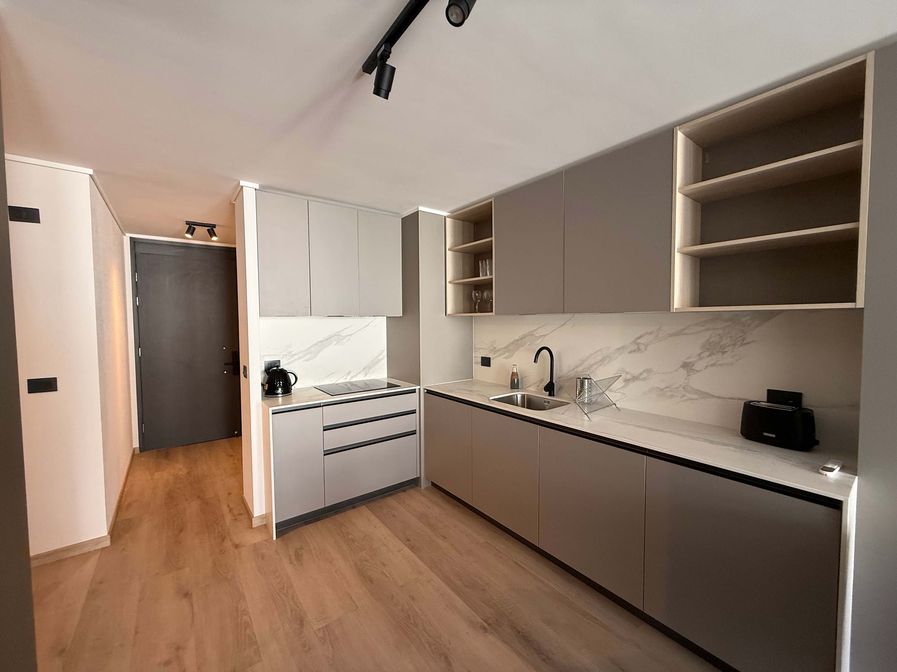 Sleek, modern kitchen with marble accents and ample storage. Perfect for culinary enthusiasts in a cozy studio setting.