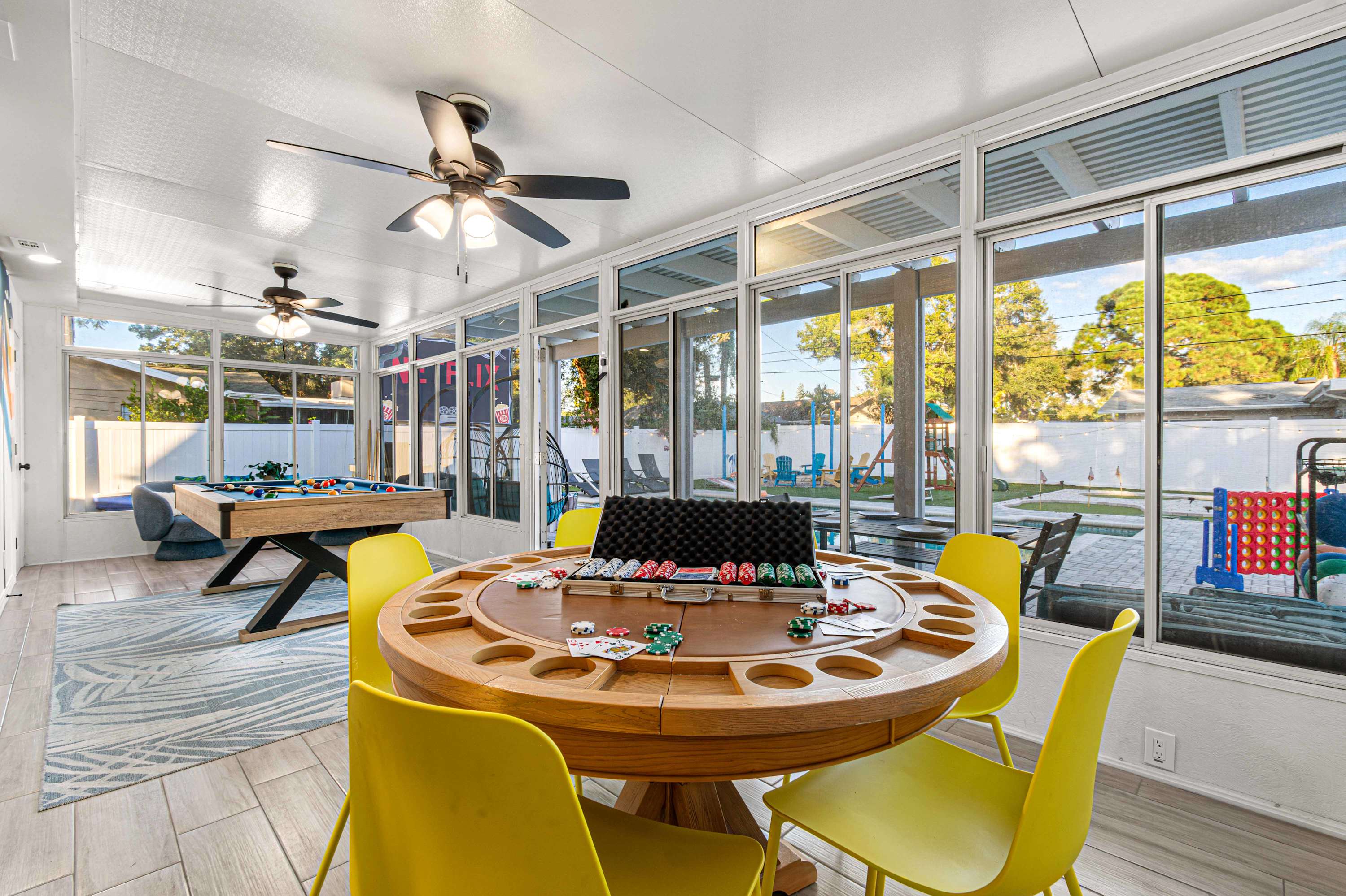 Game room that features a poker table and a pool table opening to the backyard