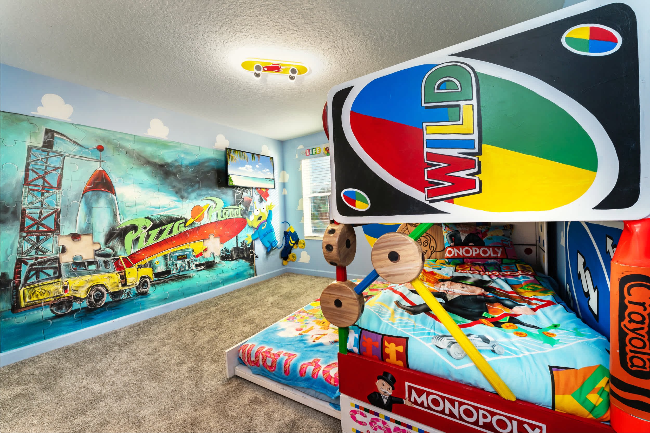 Experience a whimsical stay in this game-themed room with a 'Pizza Planet' mural and playful decor, perfect for family fun!