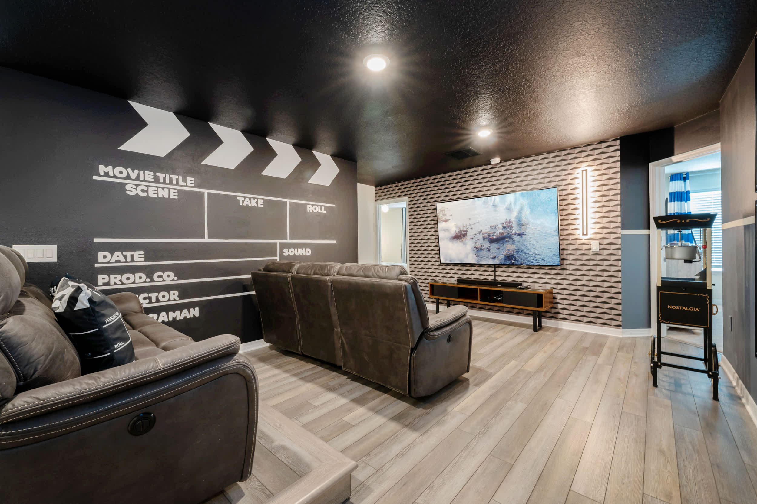 Enjoy movie nights in your private theater with plush seating, a large screen, and a nostalgic popcorn machine for the perfect cinematic experience.