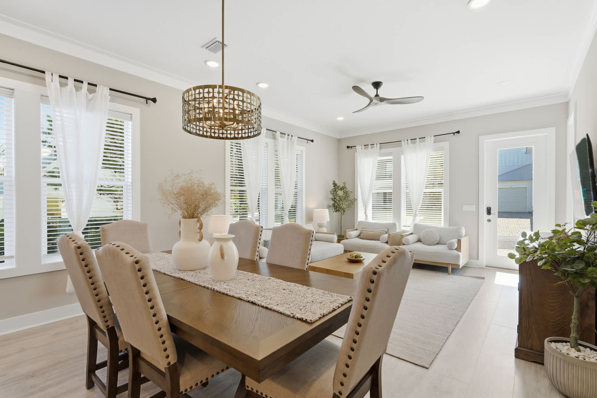 38 W Willow Mist Rd – Bright dining room with a wooden table, soft seating area, large windows, and a door leading outside.