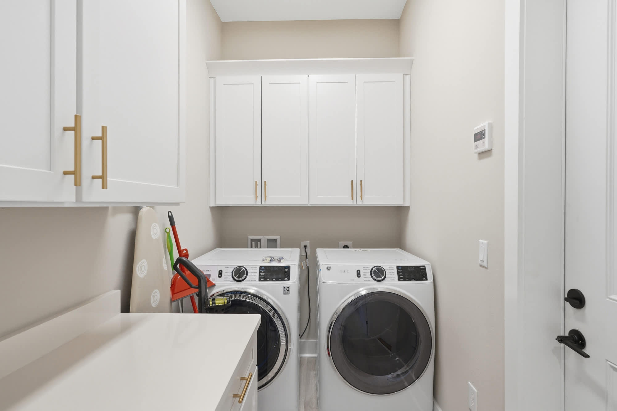 38 W Willow Mist Rd – Laundry room with white appliances, countertop, cabinets, and cleaning supplies.
