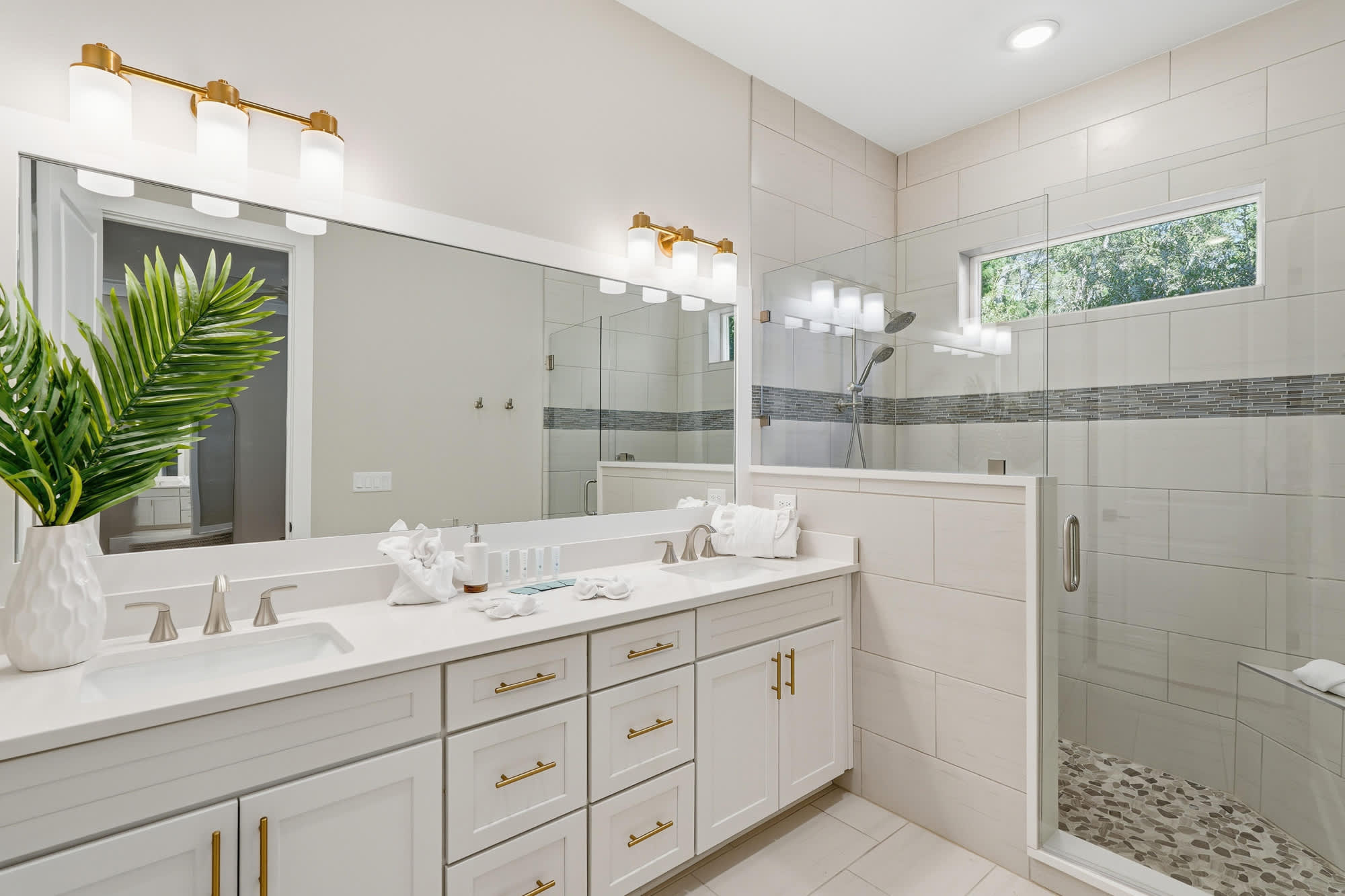 38 W Willow Mist Rd – Modern bathroom with double sink vanity, glass shower, and large mirror. Green plant in a vase.