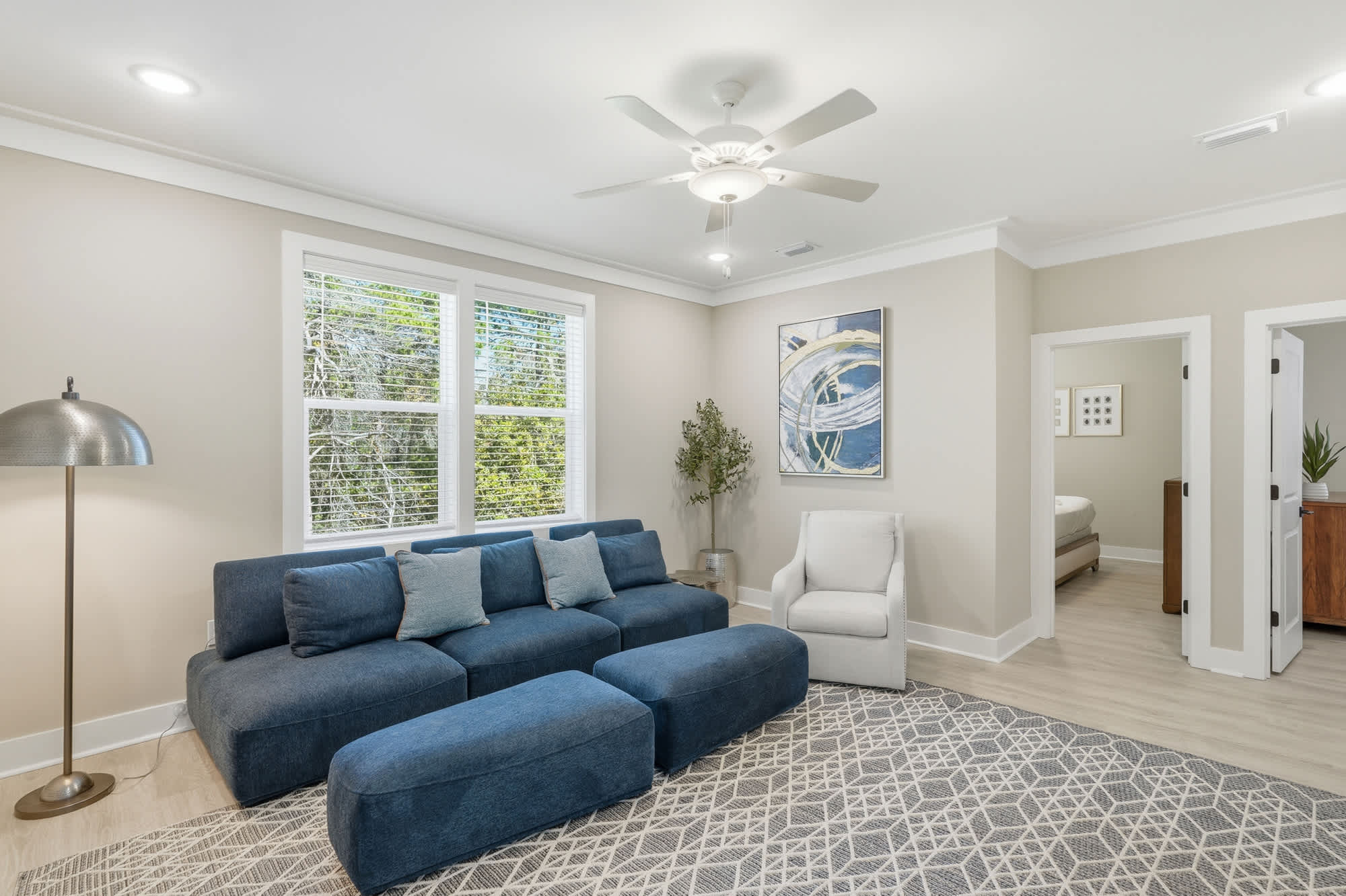 38 W Willow Mist Rd – Living room with blue sectional sofa, light rug, lamp, and adjacent doorway leading to a bedroom.