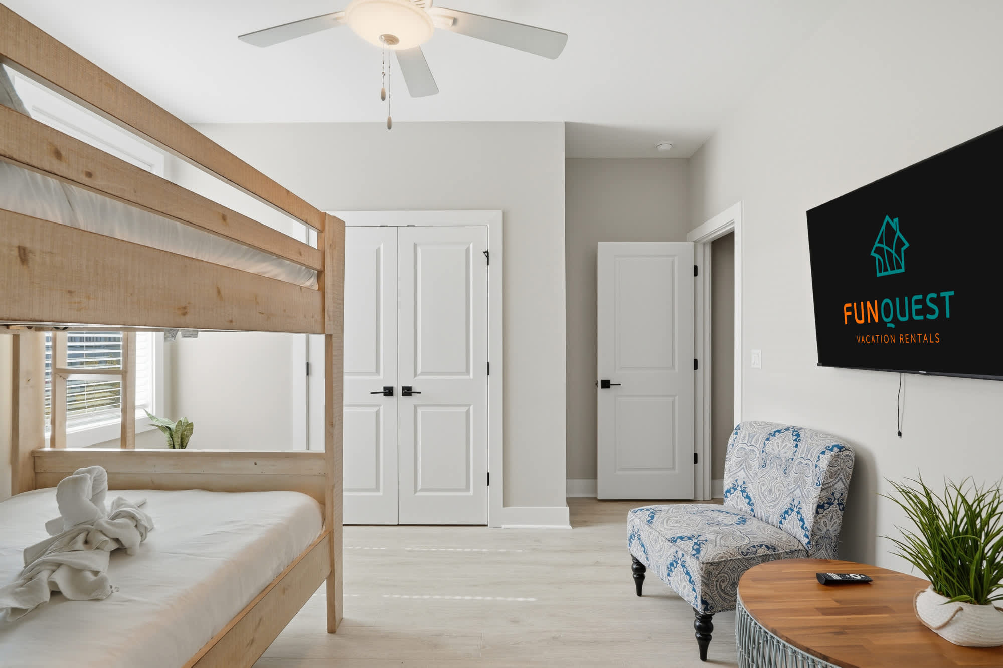 38 W Willow Mist Rd – Bunk bed with white linens, blue-patterned chair, and wall-mounted TV in bright bedroom.