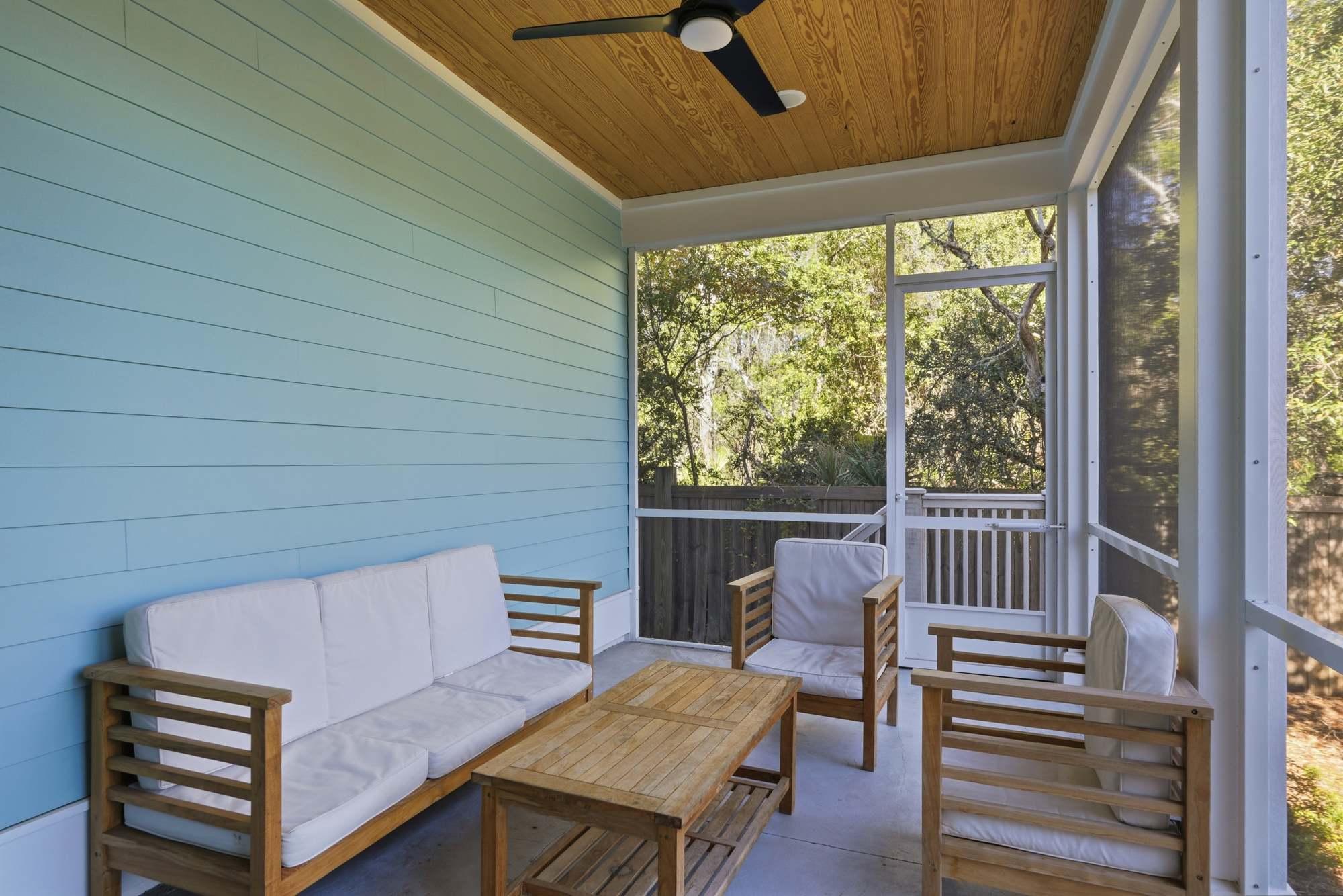 38 W Willow Mist Rd – Screened porch with wooden furniture and light blue walls, surrounded by greenery.