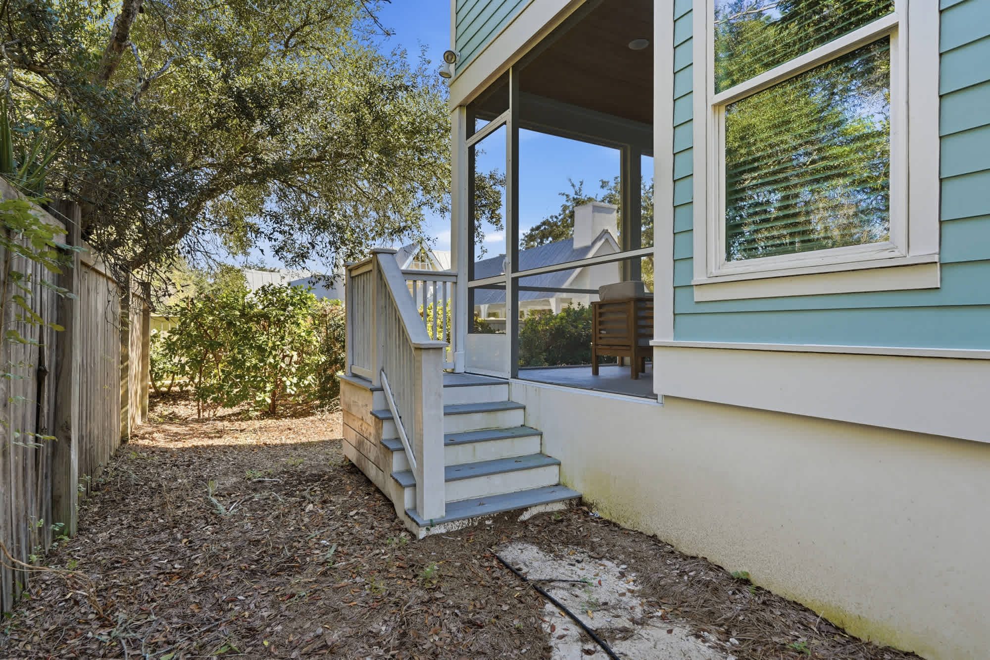 38 W Willow Mist Rd – Exterior view of a house with a staircase leading to a screened porch surrounded by greenery.