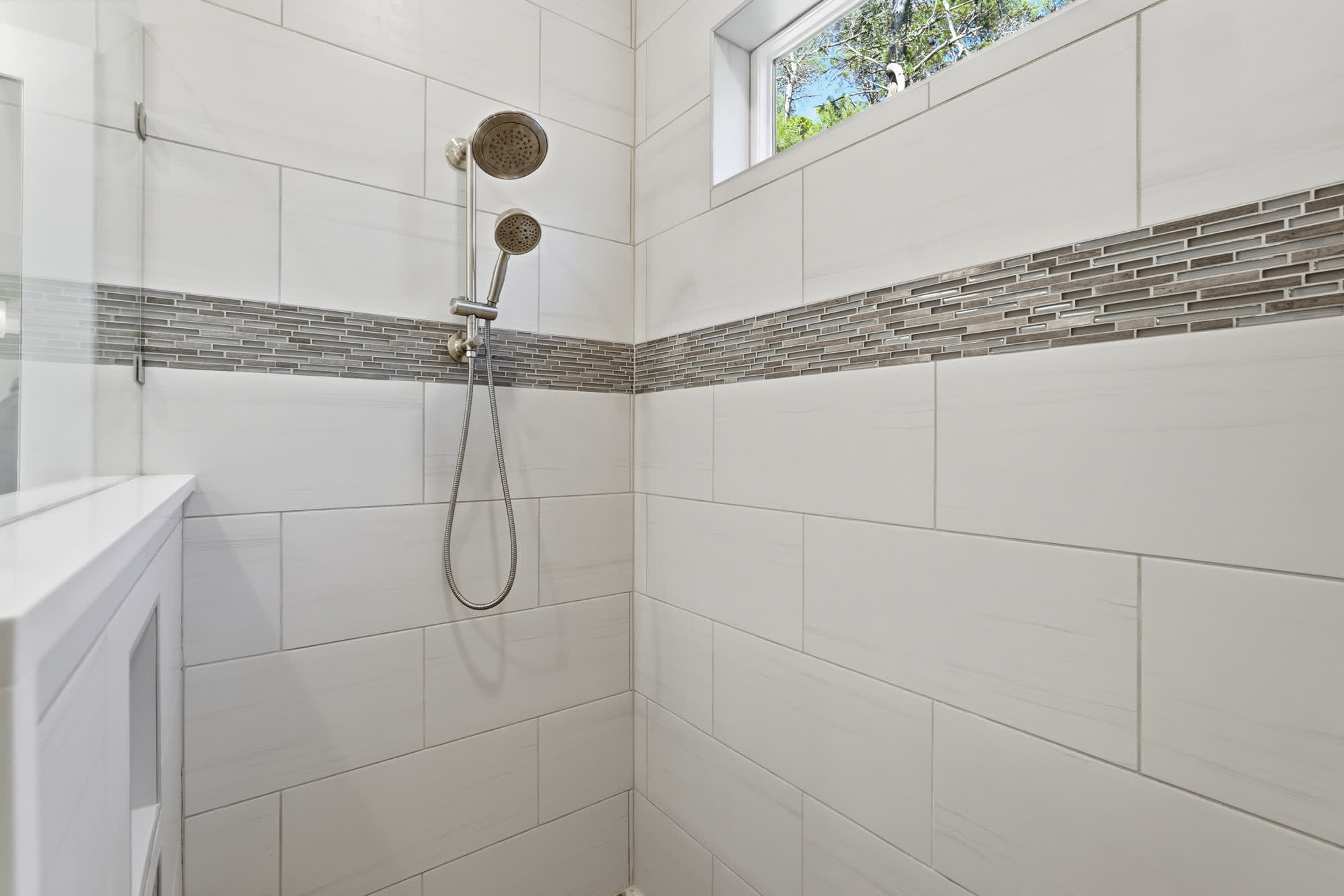 38 W Willow Mist Rd – Modern shower with white tiles, glass wall, and dual showerheads. Small window visible.