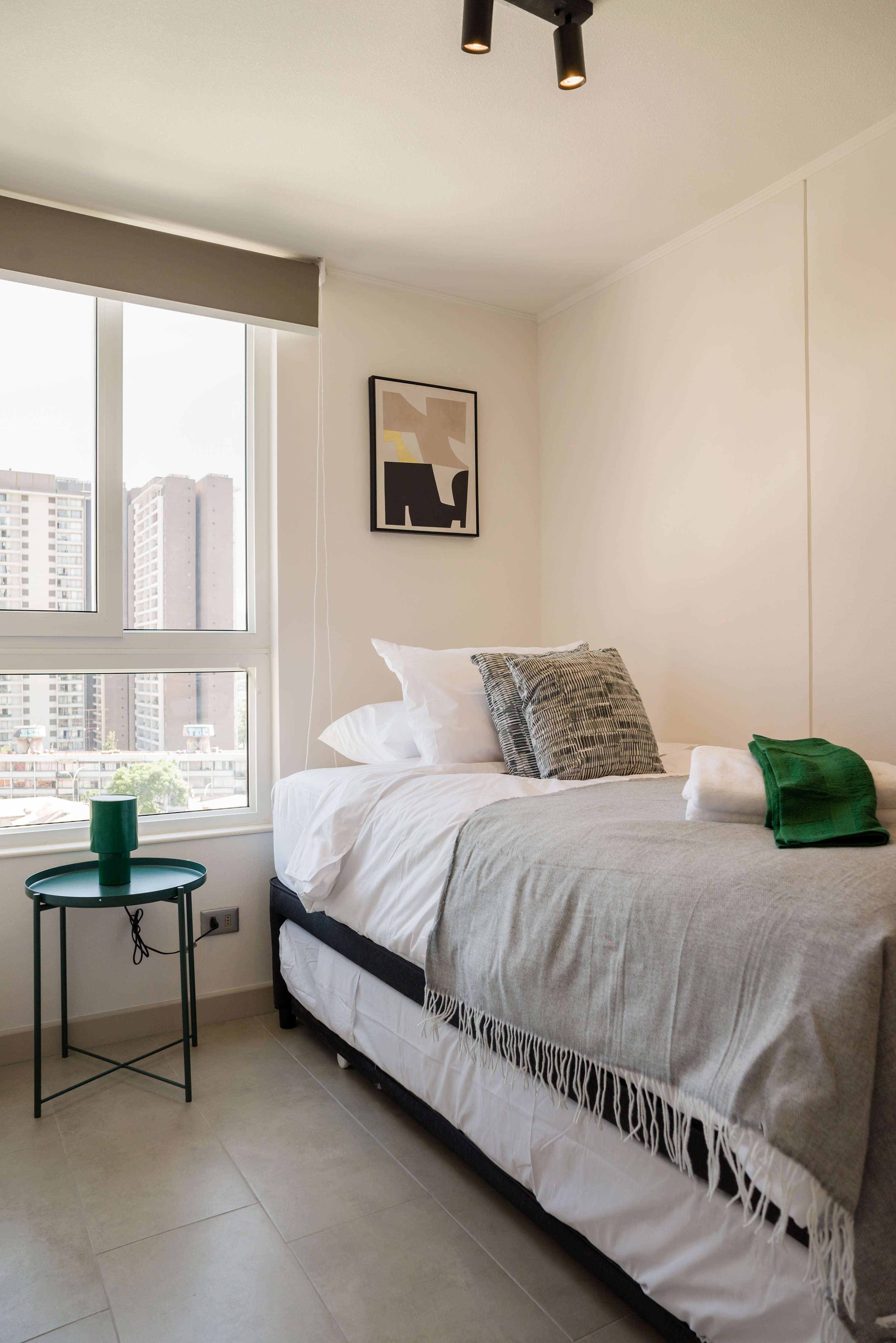 Cozy bedroom with stunning city views, modern decor, and natural light for a restful stay in Chile.
