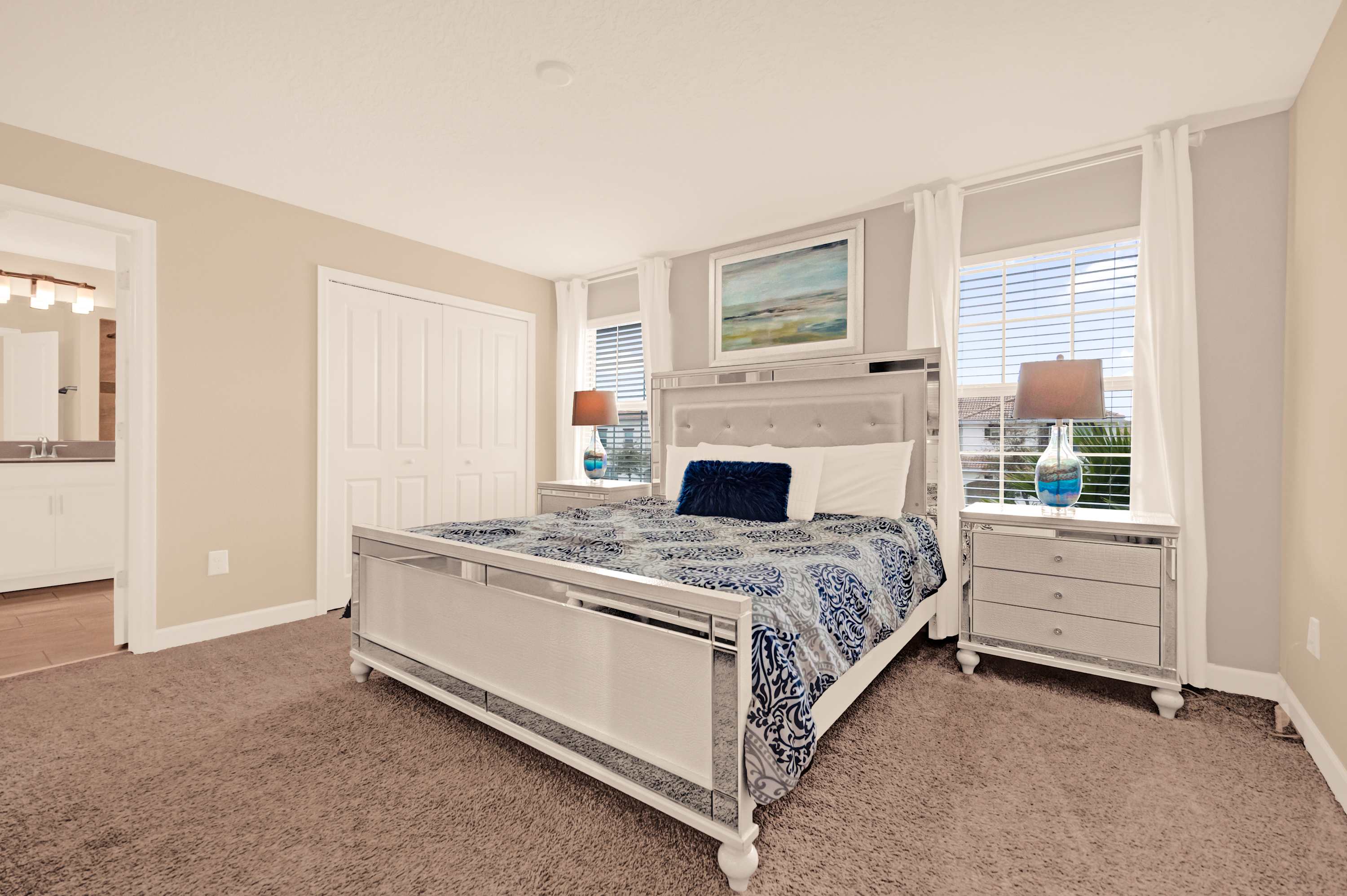 Relax in this elegant bedroom featuring a plush bed and natural light, perfect for a restful stay.