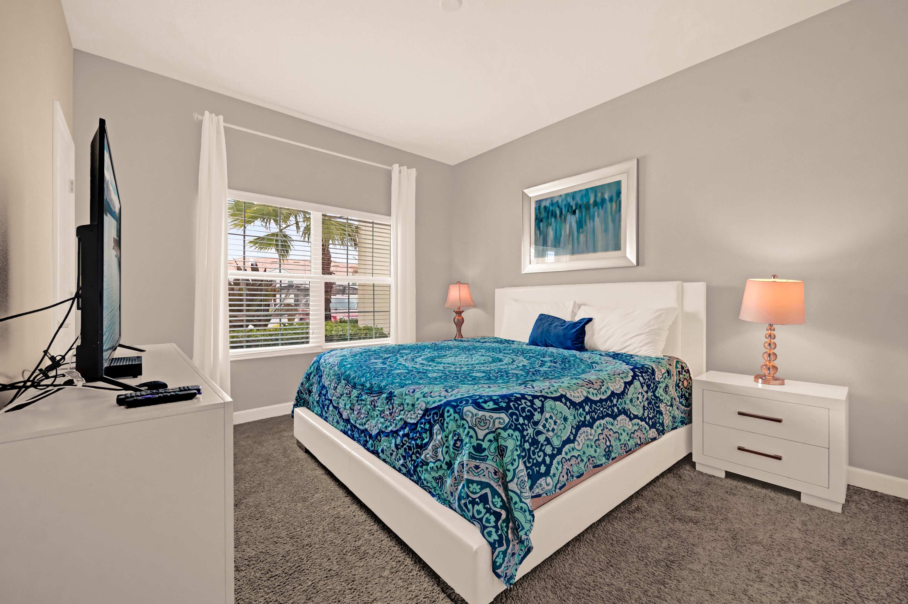 Relax in this cozy bedroom with a vibrant blue theme and natural light from the large window.