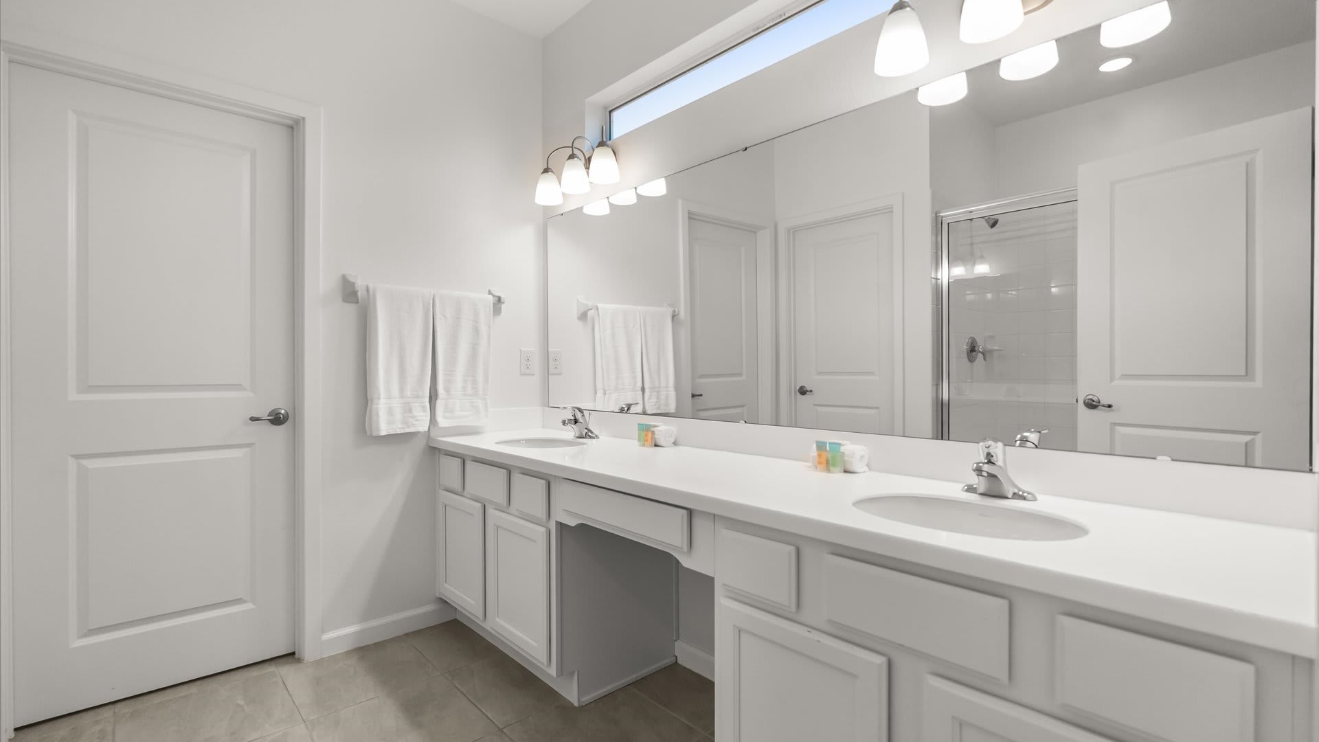 Spacious en-suite bathroom with dual basins and a spacious standing shower