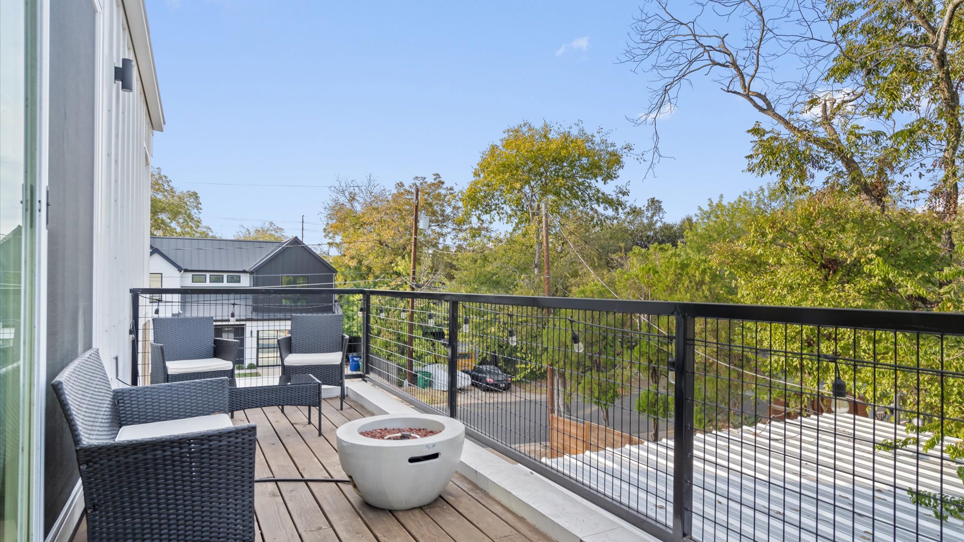 Second-floor balcony with outdoor seating and tree-top views