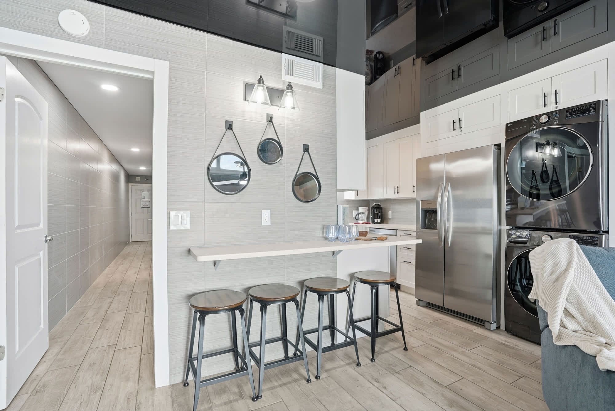 The Summit 1217 – Modern kitchen area with a bar, stools, and stainless steel appliances.