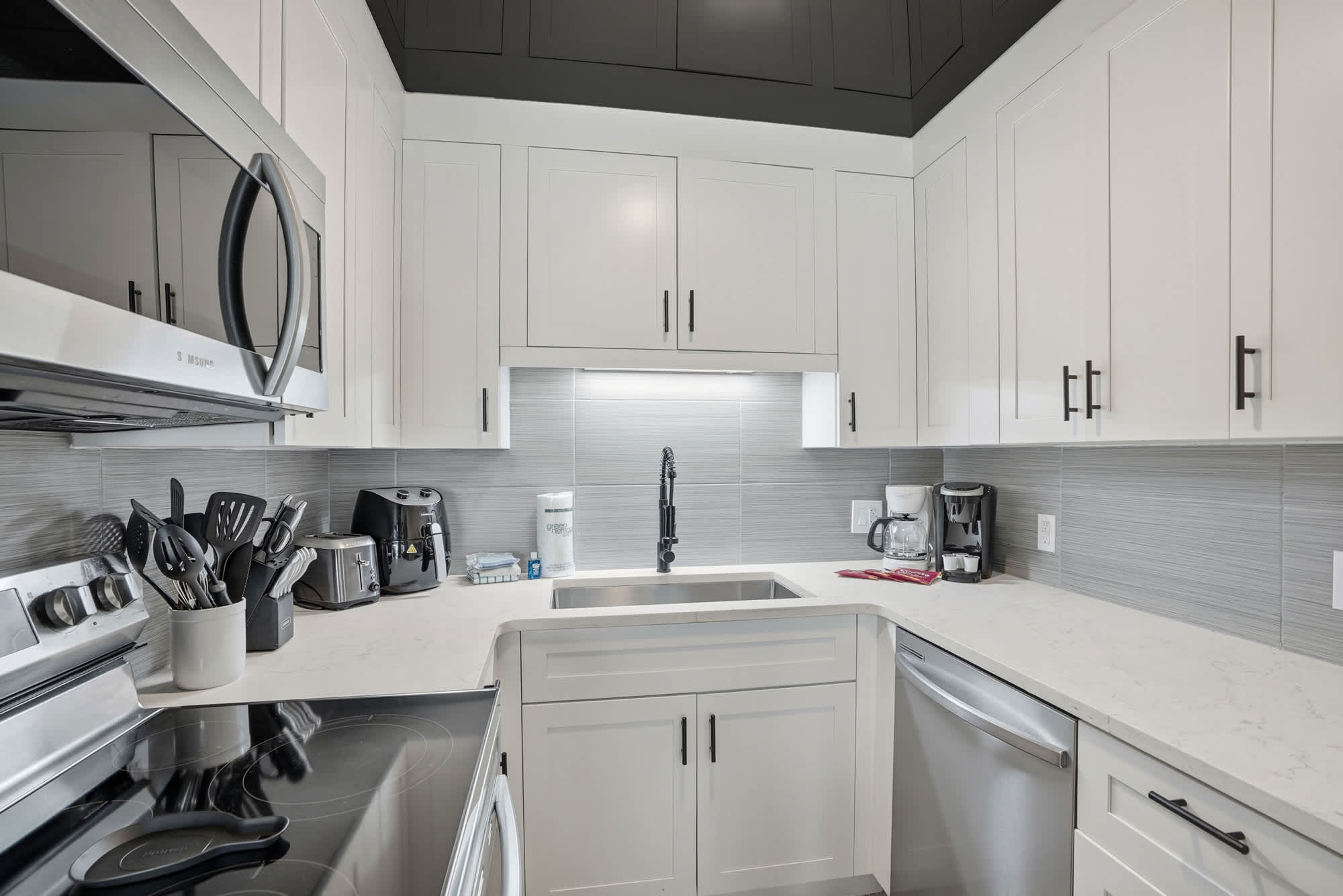 The Summit 1217 – Modern kitchen featuring stainless steel appliances, granite countertops, and white cabinetry with a sleek design.