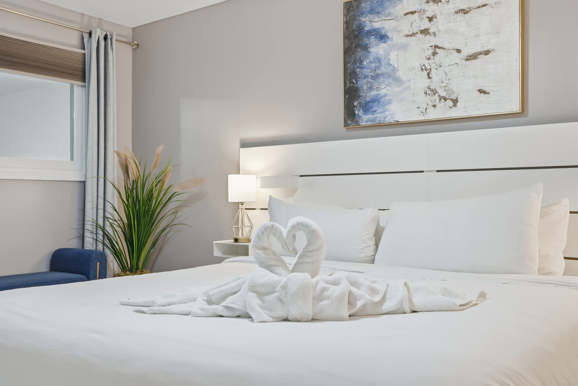 The Summit 1217 – Modern bedroom with a white bed, decorative towel swan, and soft lighting.