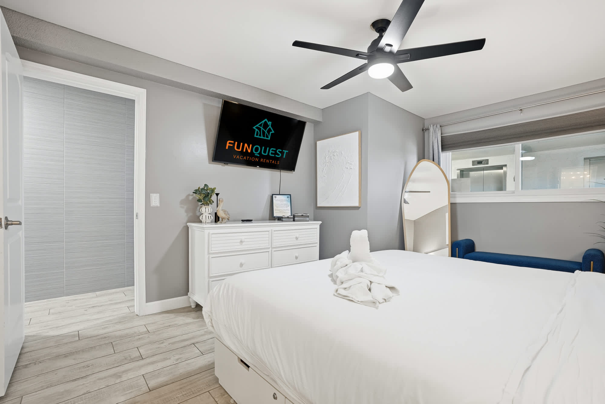 The Summit 1217 – Bedroom with a bed, dresser, TV, seating area, and window with natural light.