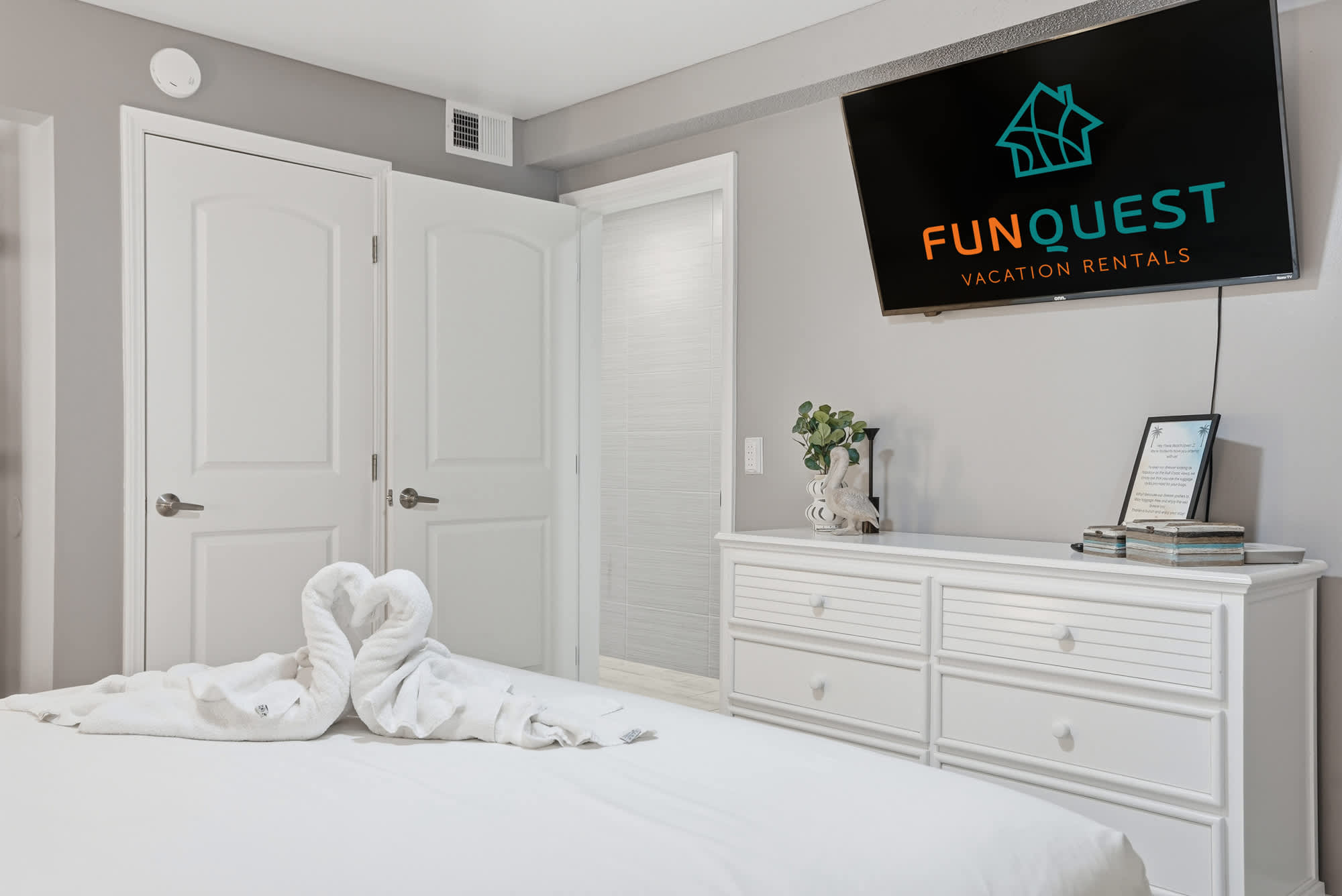 The Summit 1217 – Bright bedroom with white bedding, TV on the wall, and decorative elements including towels shaped like swans.