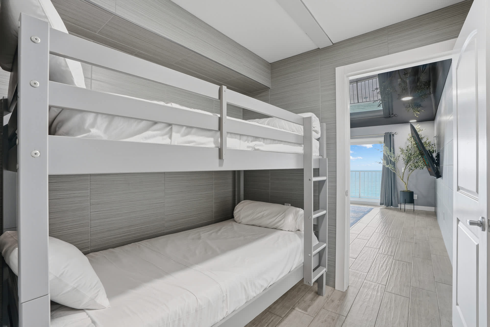 The Summit 1217 – Bunk bed in a room with a view of the ocean through an adjoining door.