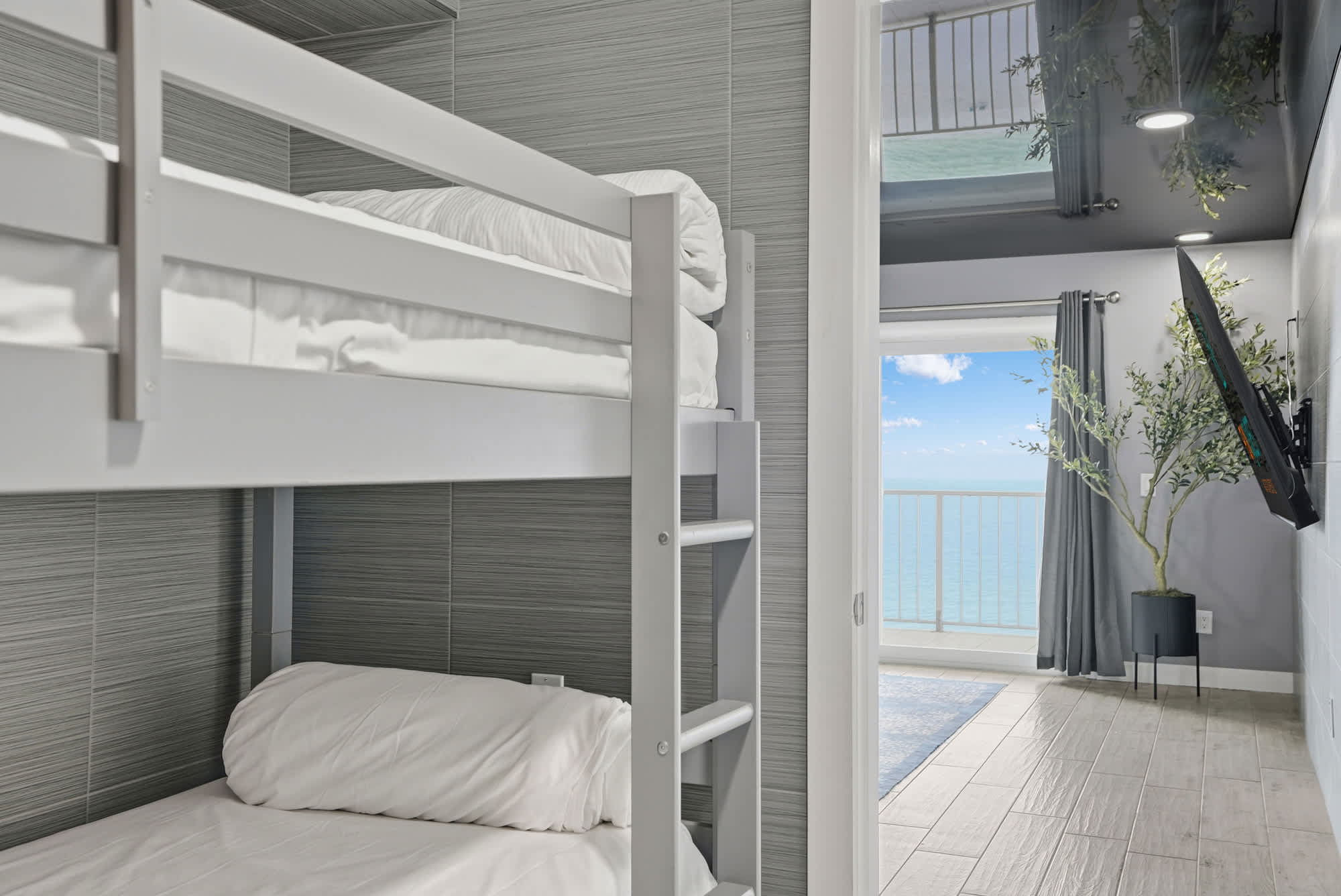The Summit 1217 – Bunk beds in a room with a view of the ocean and balcony.