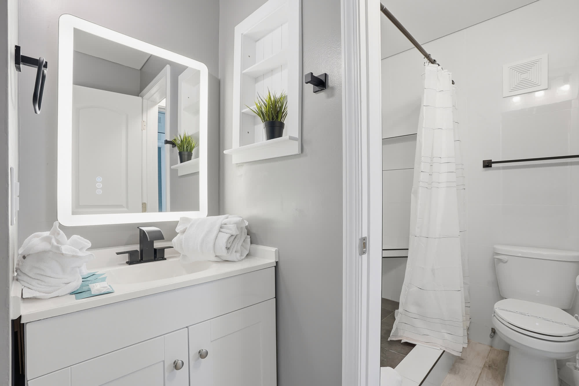 The Summit 1217 – Bathroom with a mirror, vanity, towels, shower curtain, and modern fixtures.