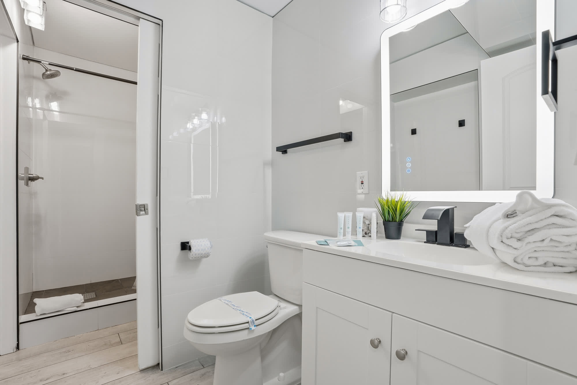 The Summit 1217 – Modern bathroom with shower, toilet, sink, mirror, and towels.