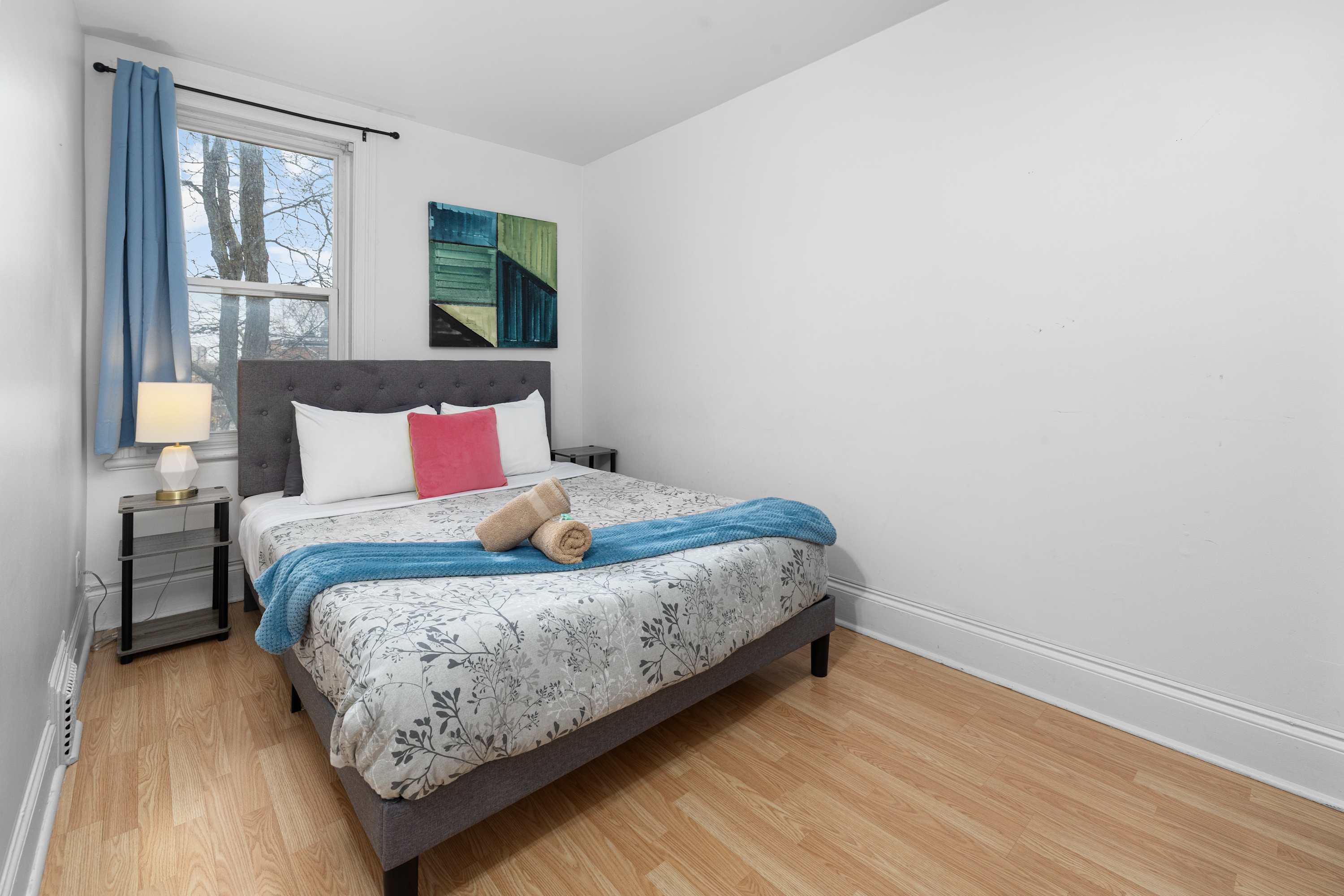Queen Bedroom with fresh linens and a bedside lamp.
