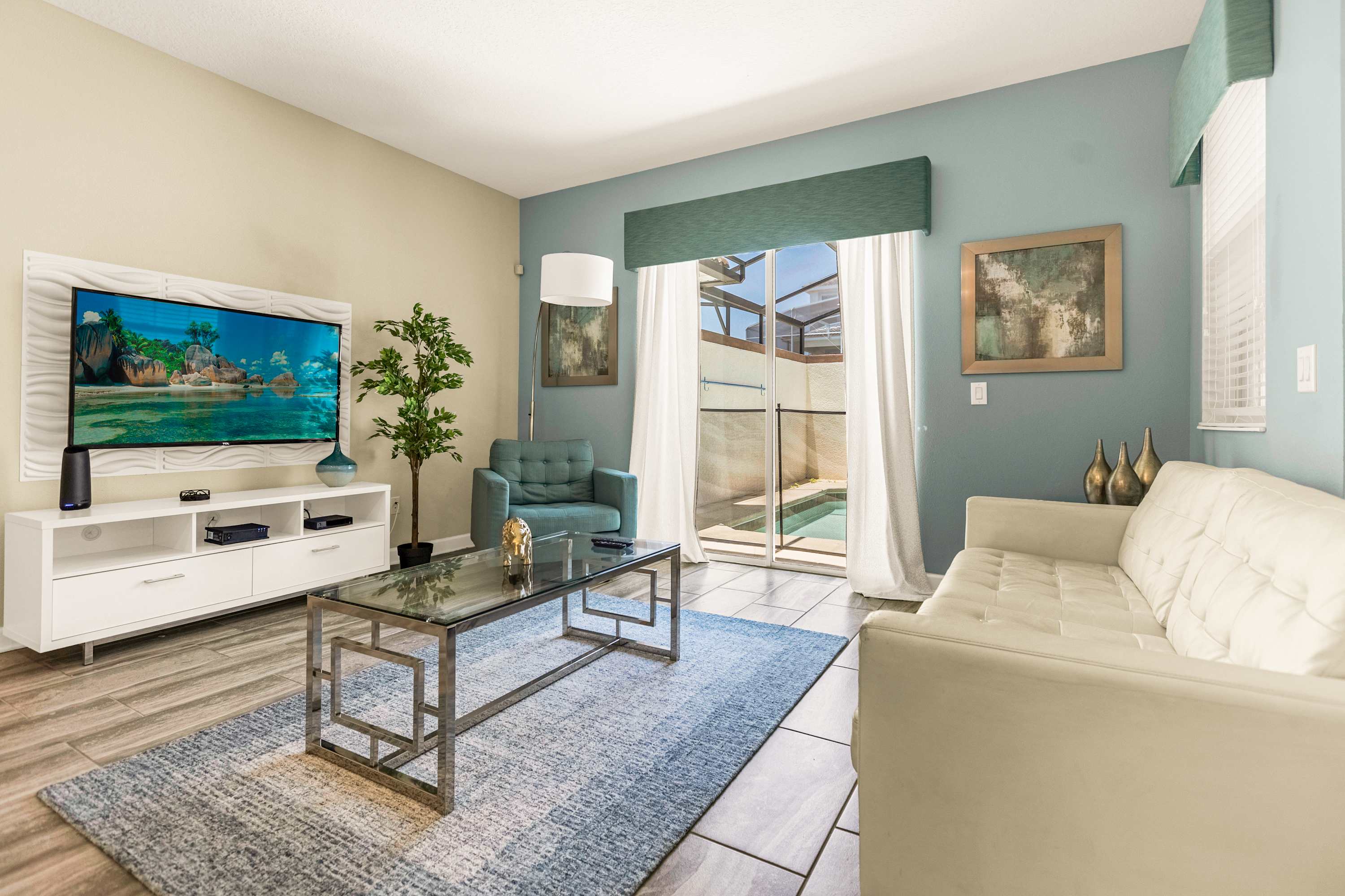 Relax in this stylish living room with a large TV and access to a private pool area, perfect for unwinding after a day of adventure.