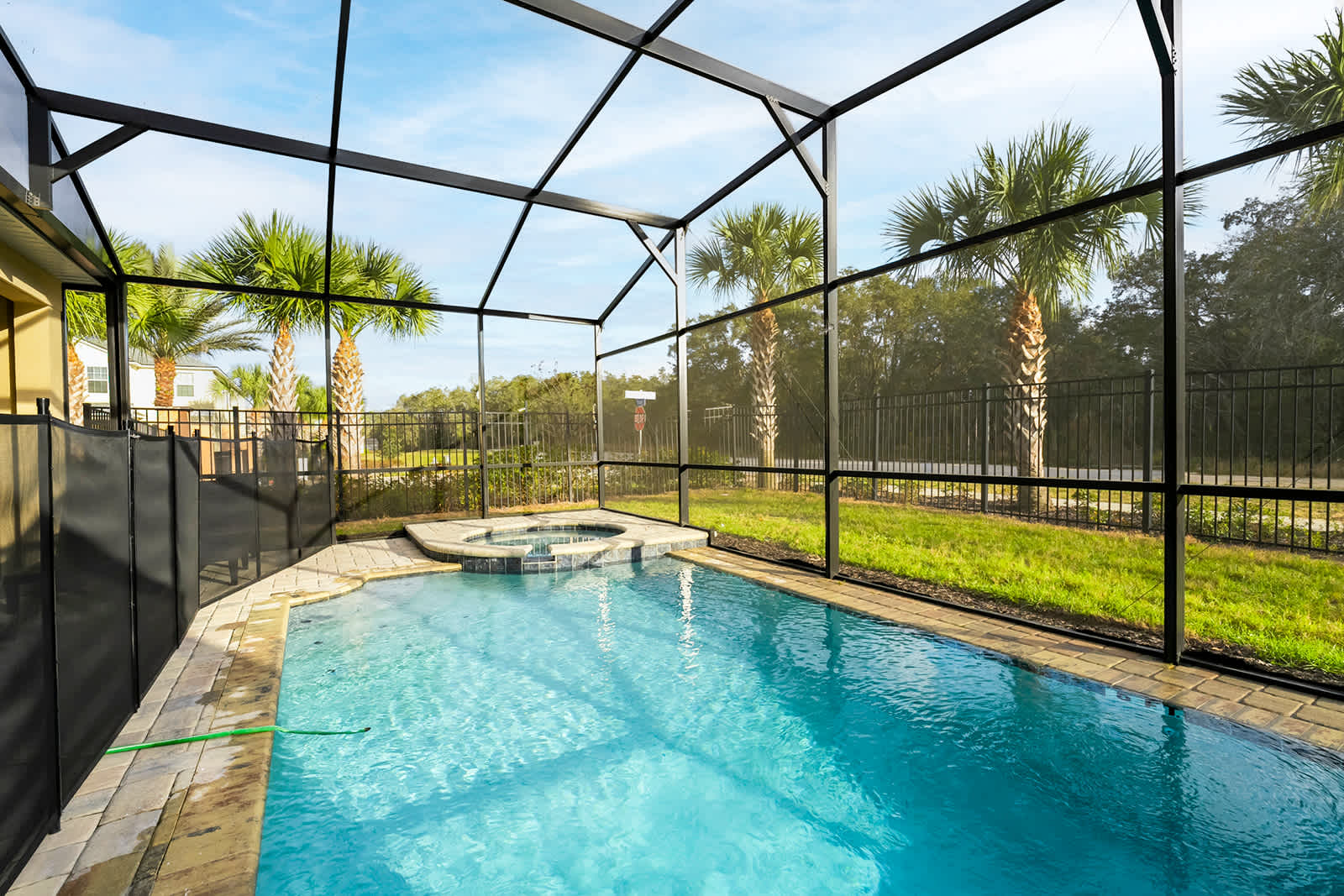 Relax in your private screened-in pool and hot tub, surrounded by lush greenery and palm trees.