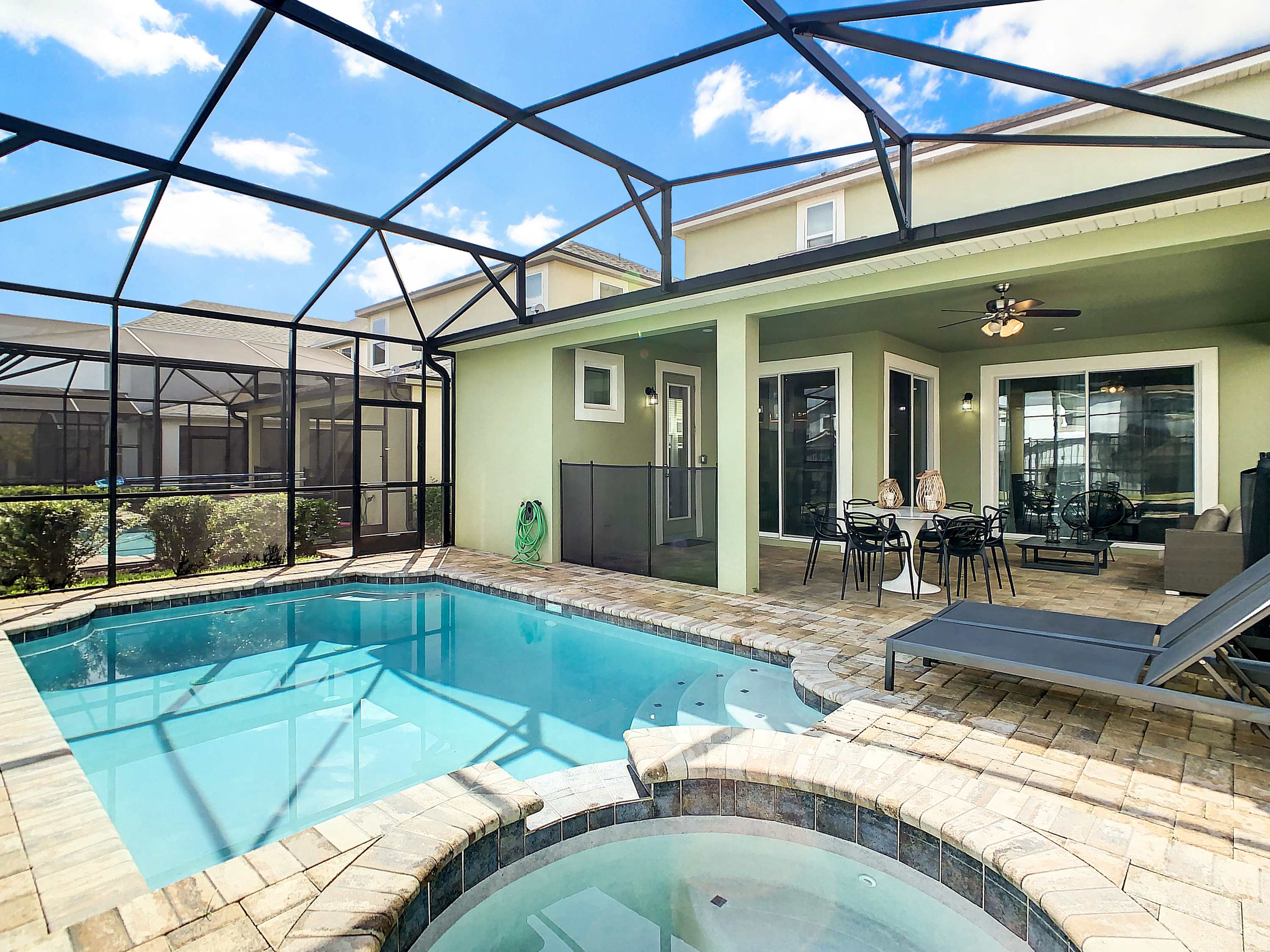 Private screened pool and spa with covered outdoor dining, lounge seating, and direct views of the spacious villa.