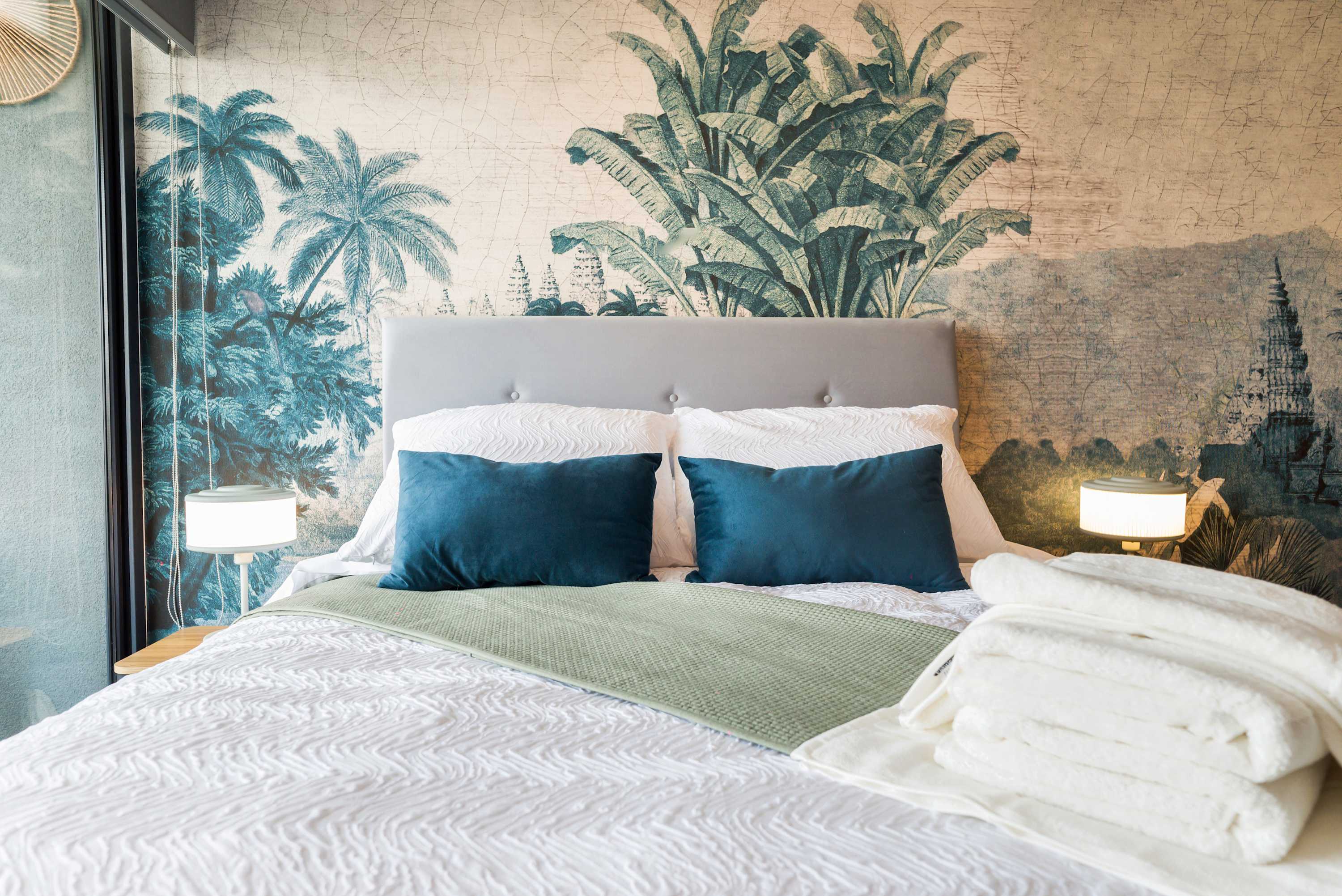 Relax in this stylish bedroom with tropical decor and plush bedding, perfect for a cozy stay.