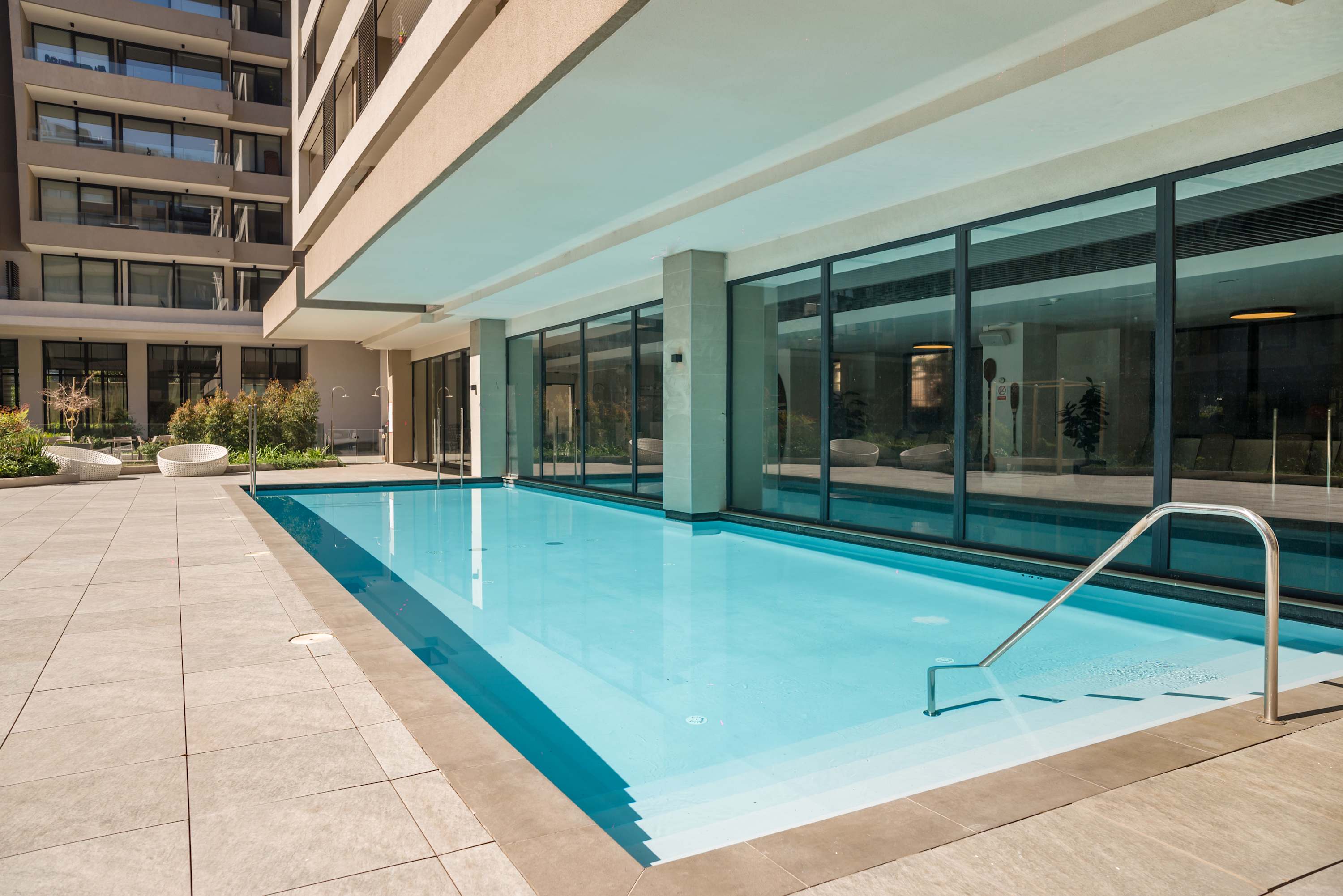 Enjoy a refreshing swim in the modern pool surrounded by lush greenery and contemporary design.