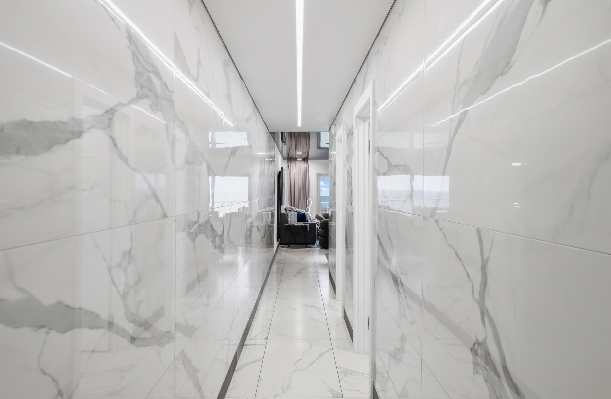The Summit 1208 – Hallway featuring marble walls, leading to a living area with a view and modern furnishings.