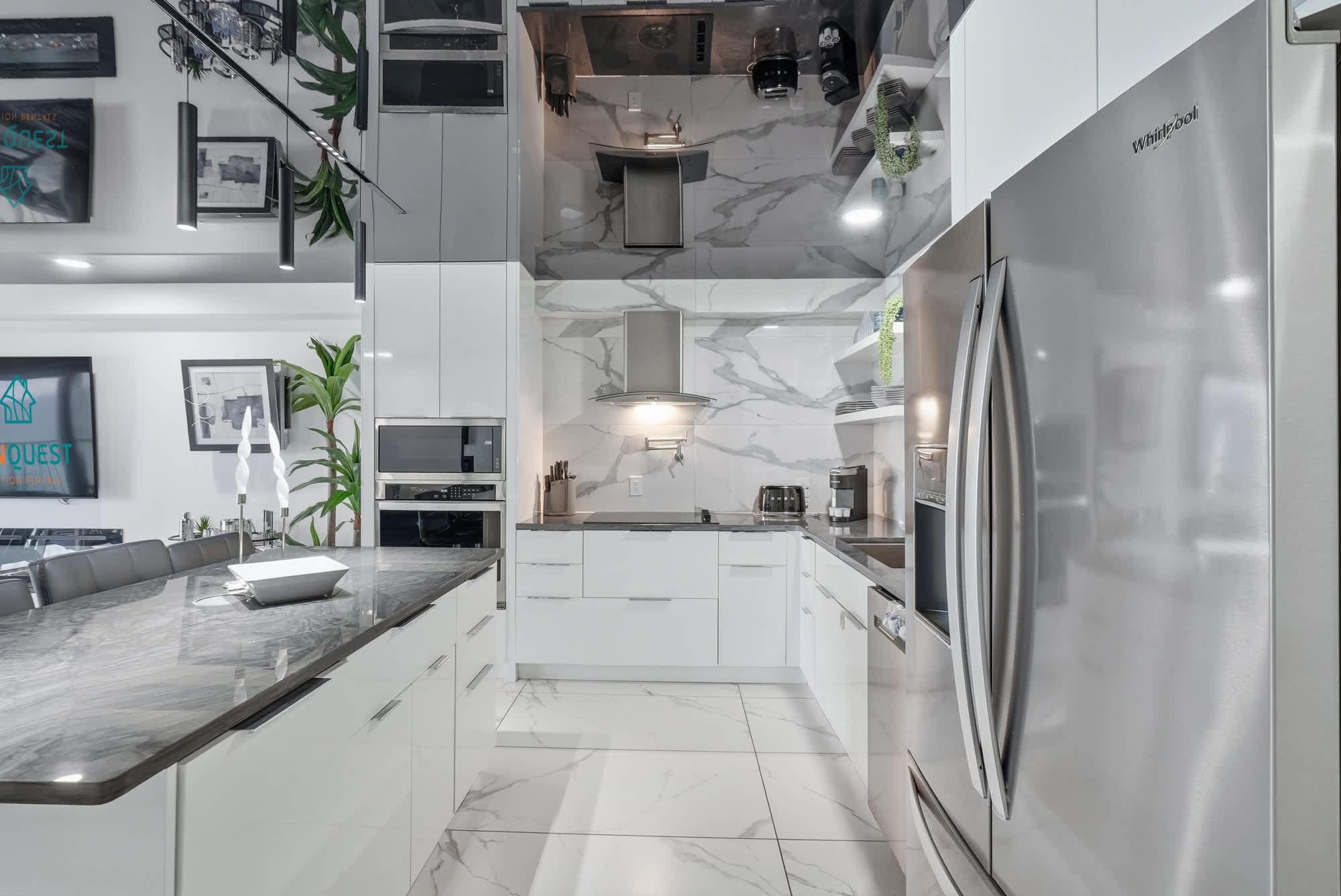 The Summit 1208 – Modern kitchen with marble countertops, stainless steel appliances, and sleek white cabinetry.