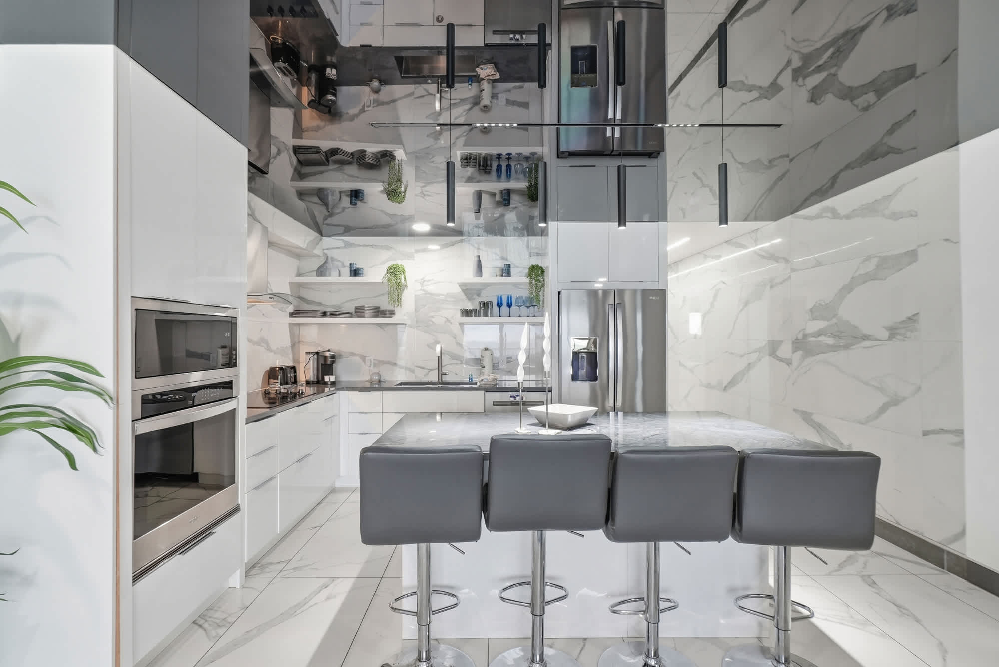 The Summit 1208 – Modern kitchen with marble countertops, stainless steel appliances, and seating at a sleek island.