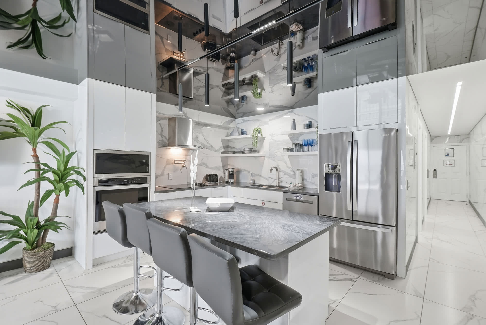 The Summit 1208 – Modern kitchen with sleek cabinetry, marble countertops, bar seating, and stainless steel appliances.