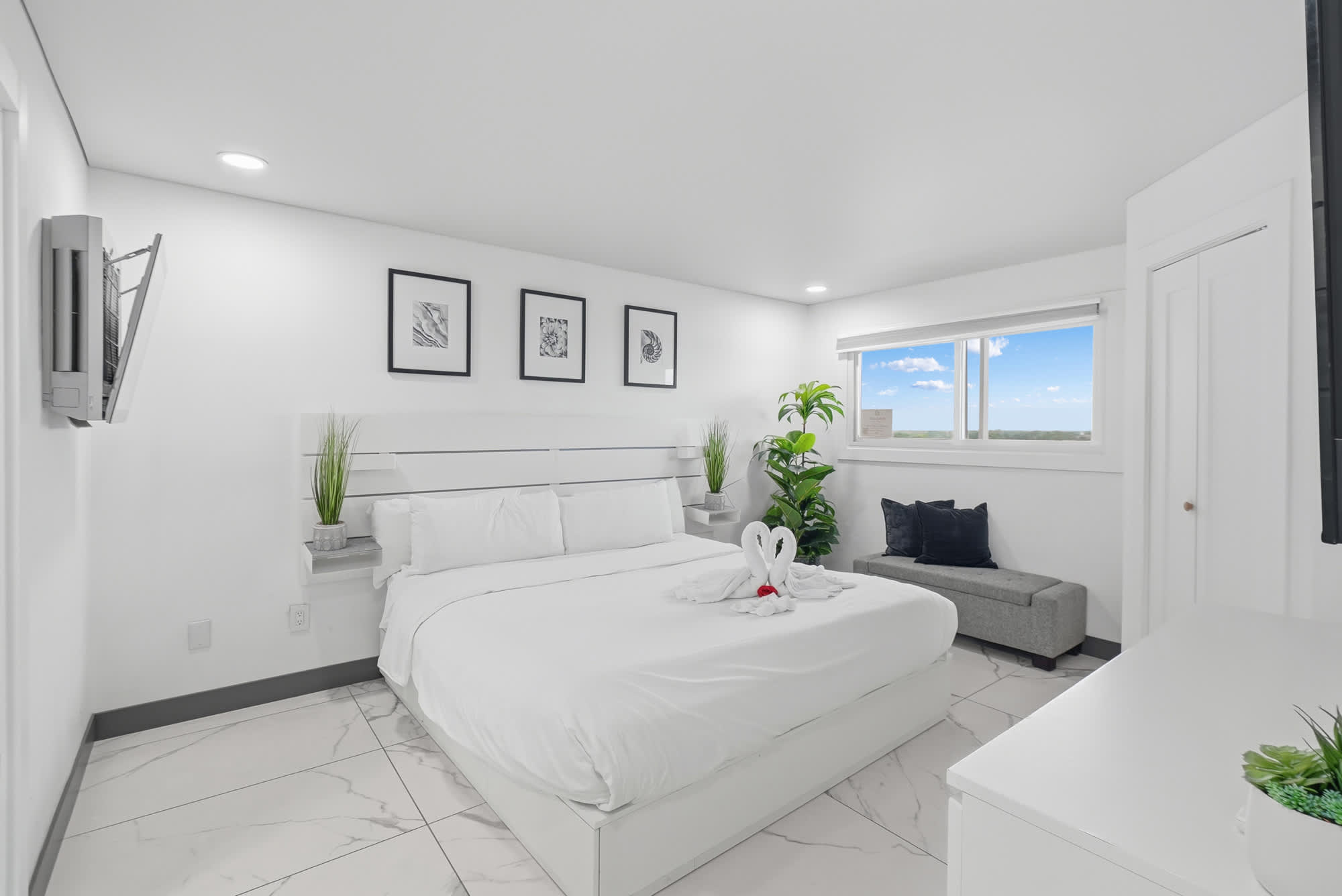 The Summit 1208 – Bright bedroom with a king bed, seating area, and window view of blue skies.