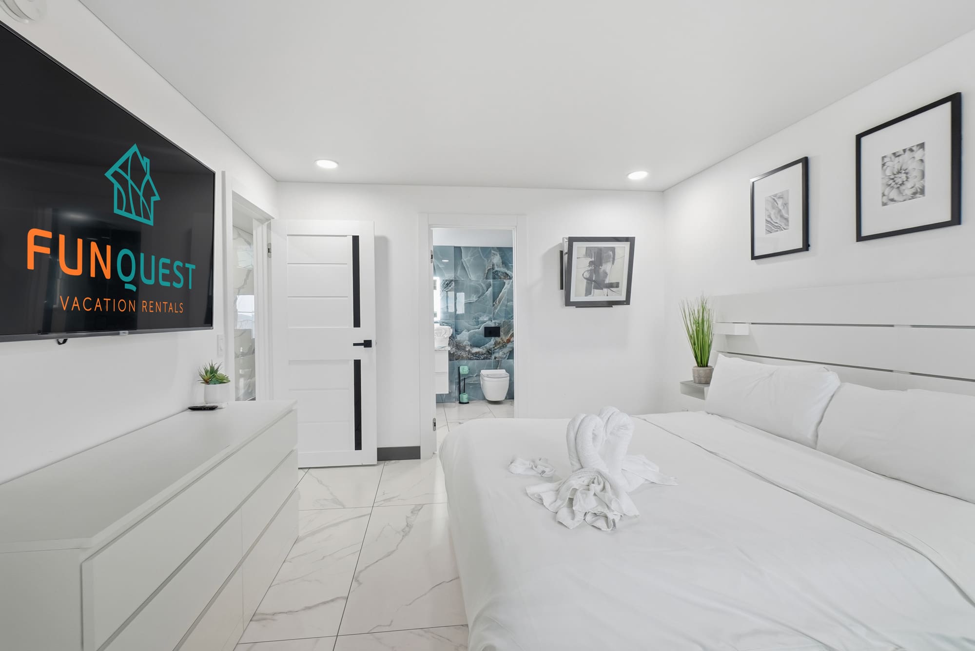 The Summit 1208 – Modern bedroom with a large bed, television, and en-suite bathroom visible through an open door.
