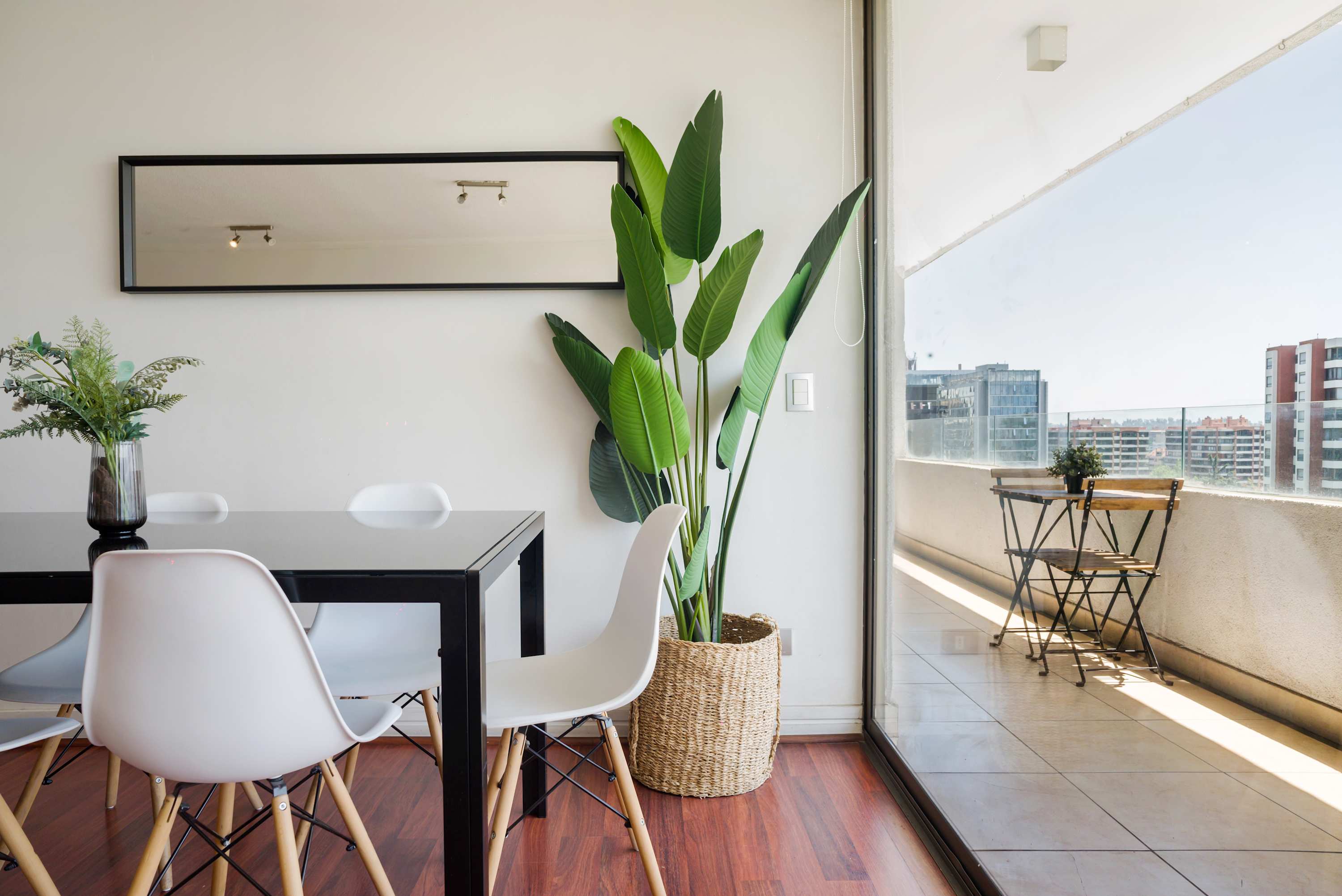 Bright dining area with a lush plant and access to a private balcony offering city views.