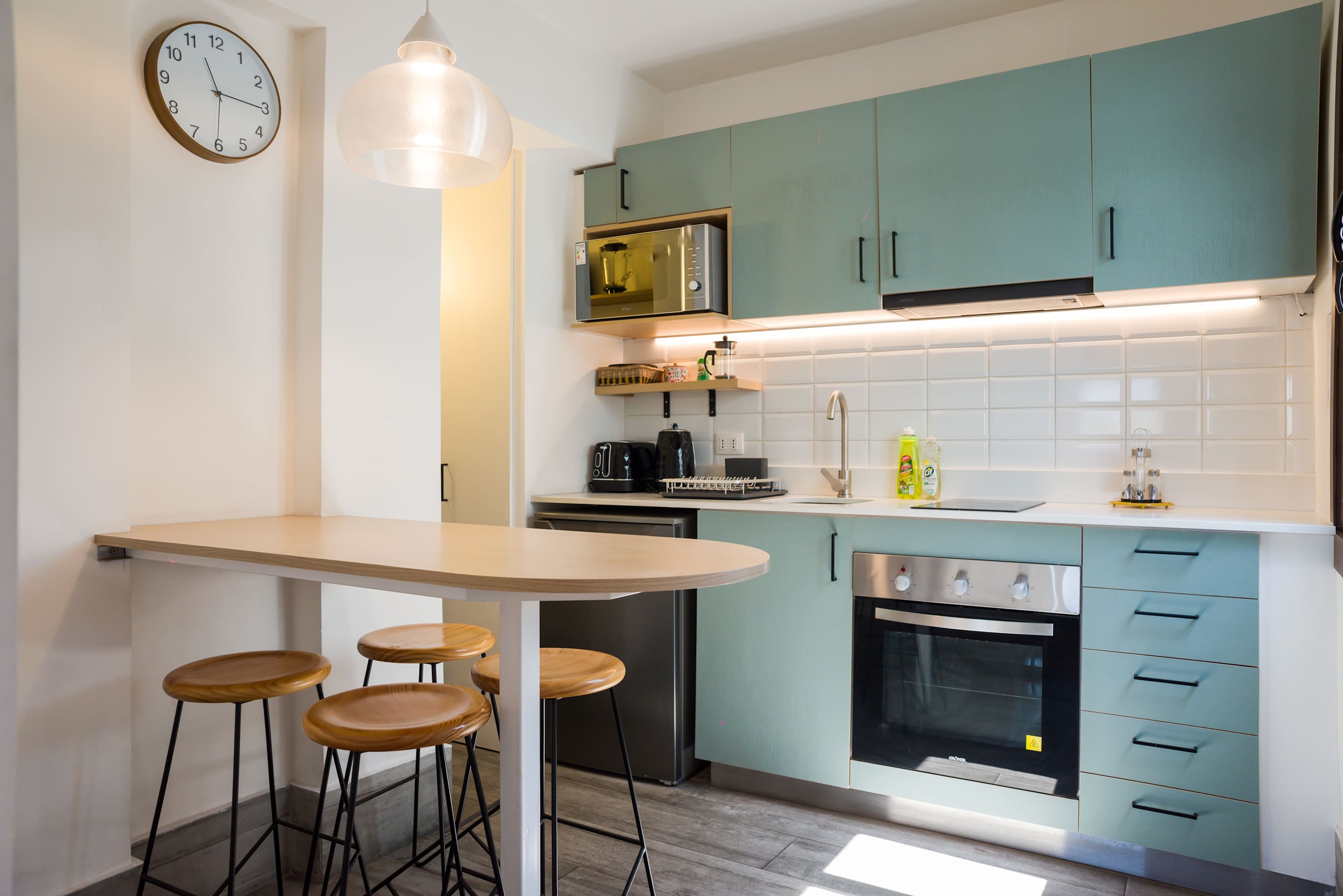 Stylish and modern kitchen with teal cabinets and a cozy breakfast bar, perfect for enjoying meals in your private studio retreat.