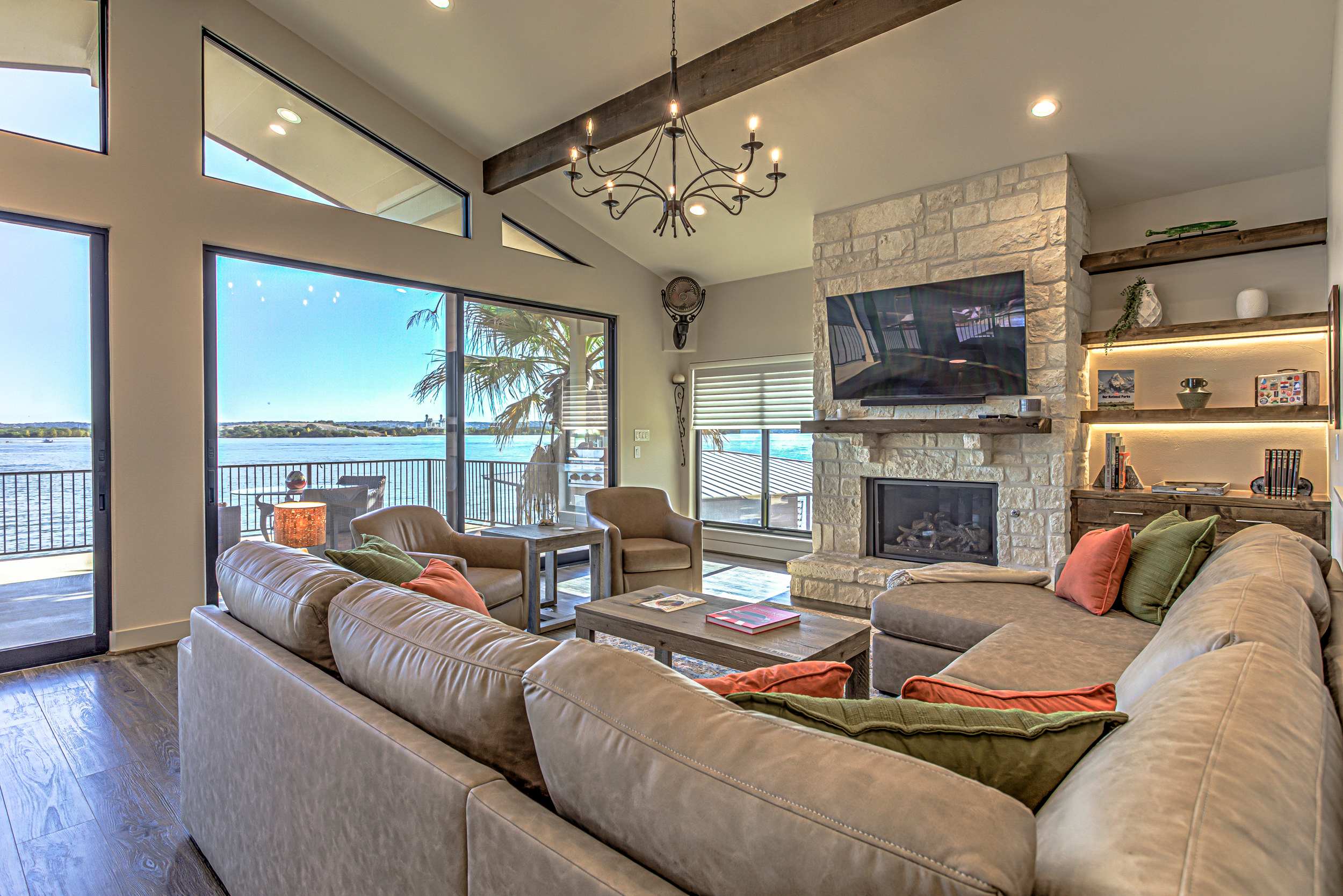 Open concept living room w/fireplace, TV, patio access, & panoramic lake views