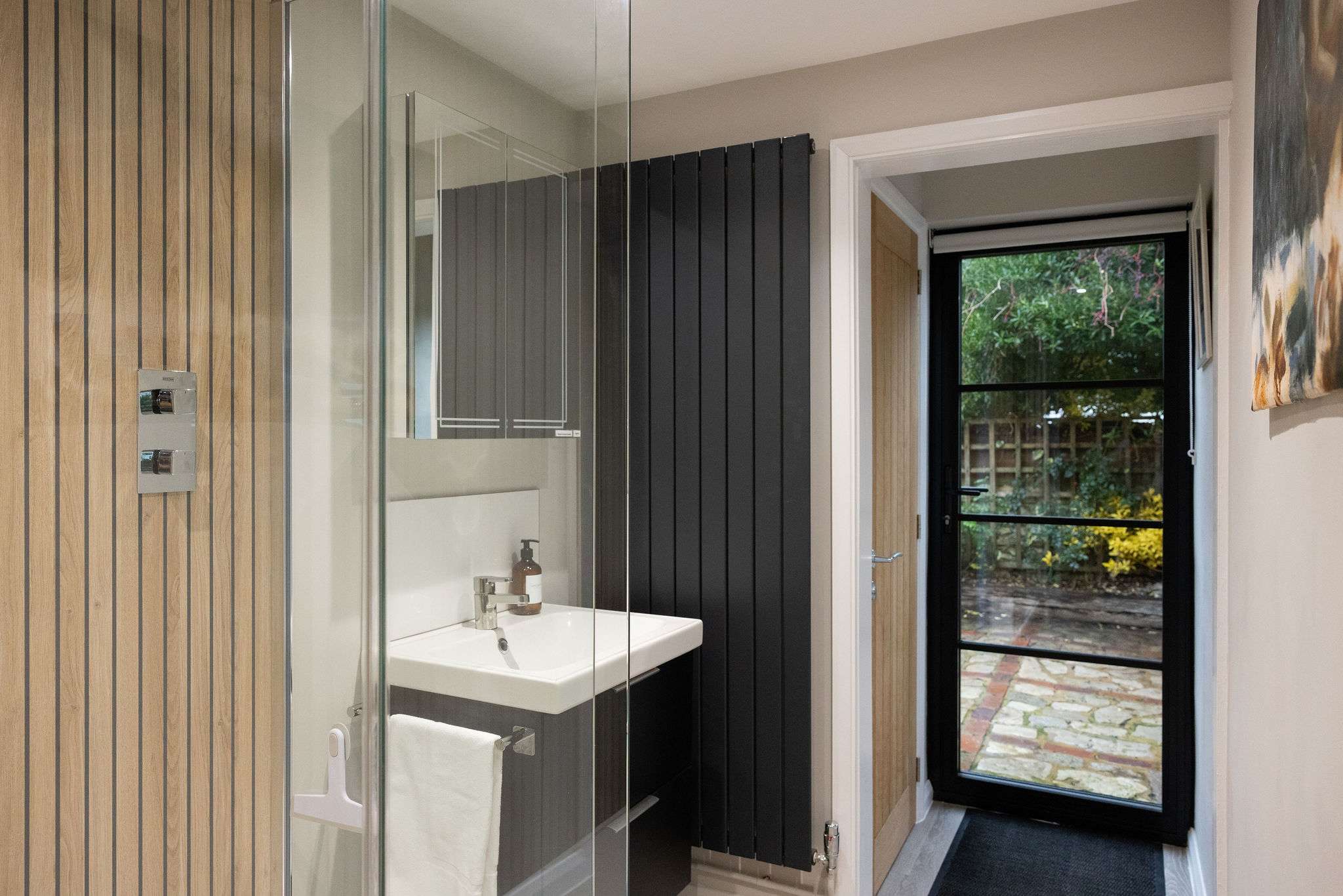 The downstairs shower room features a spacious walk-in shower with sleek fixtures and warm wood-effect detailing.