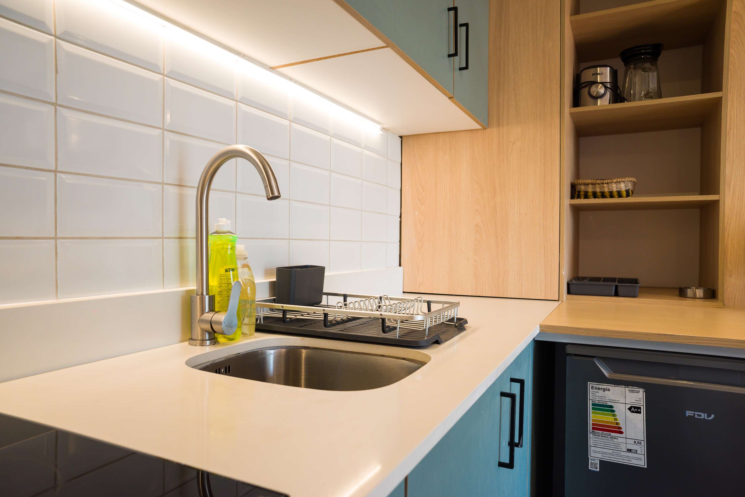 Modern and efficient kitchenette with sleek design, perfect for preparing meals in a cozy studio setting.