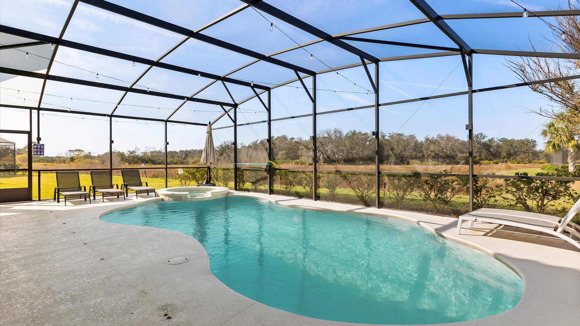 Sunny screened-in pool with peaceful nature views.