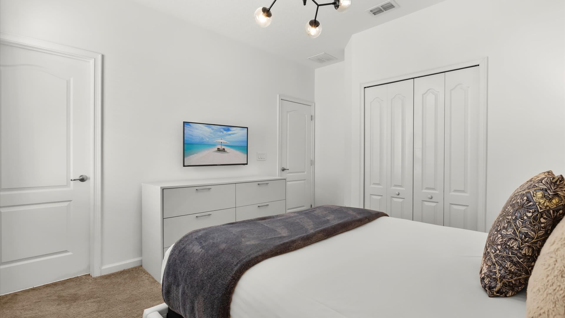 Minimalist queen bedroom with plush bedding.
