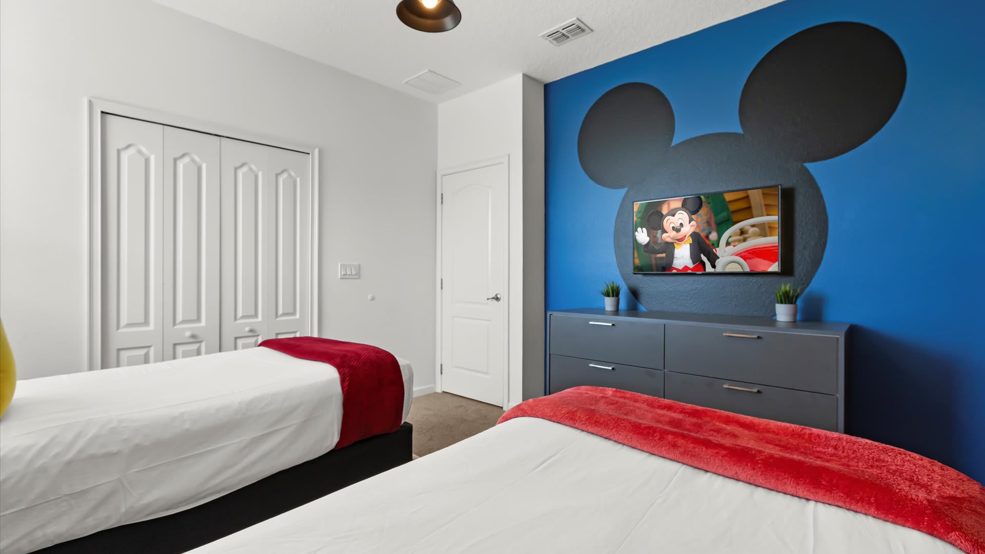 Mickey Moused themed kids’ twin room with TV and playful wall art.