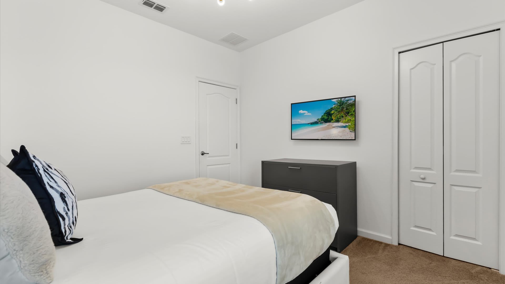 Queen bedroom with soothing tones and large windows.