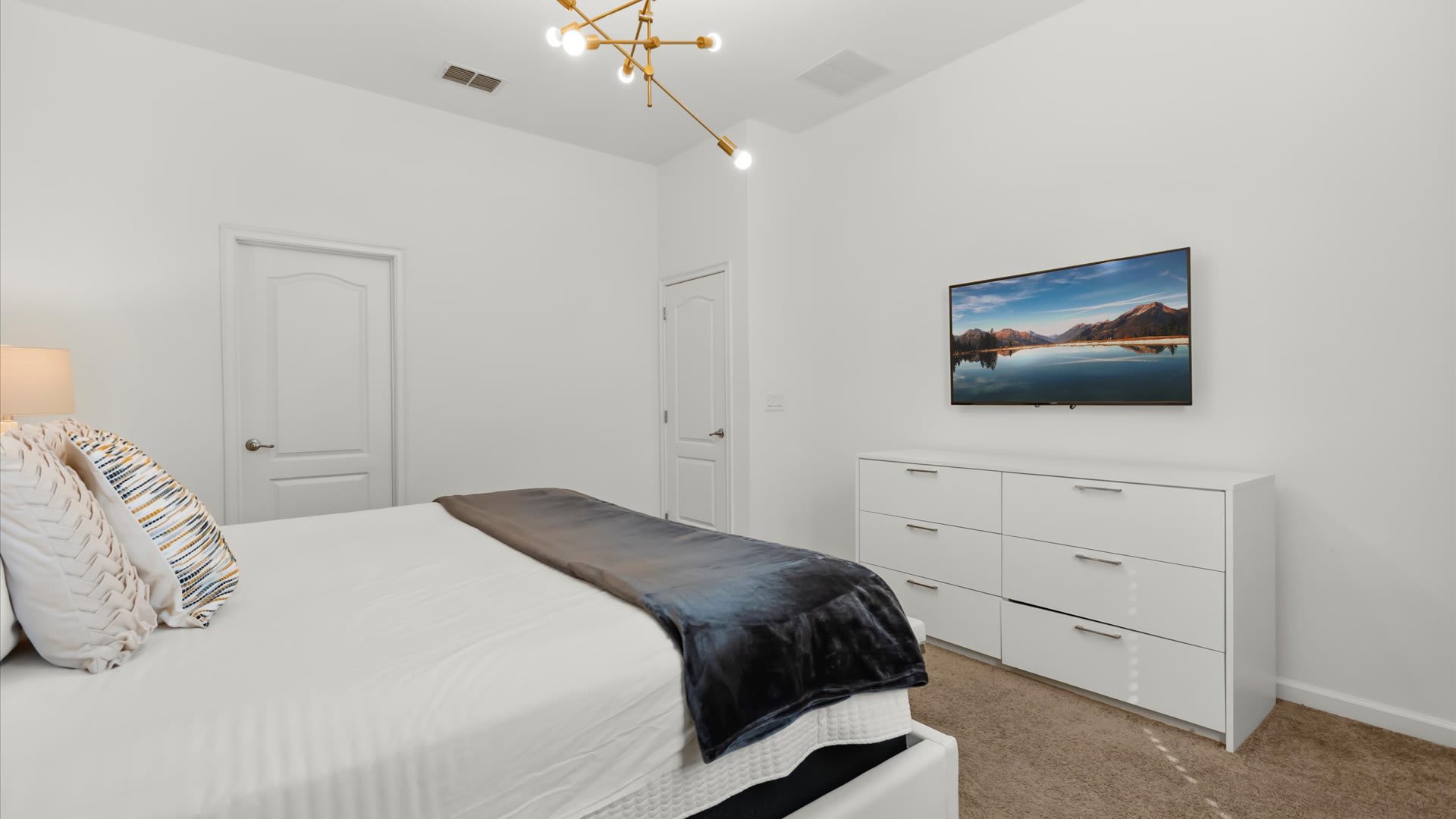 Warm queen bedroom accented with golden drapery and a smart TV.