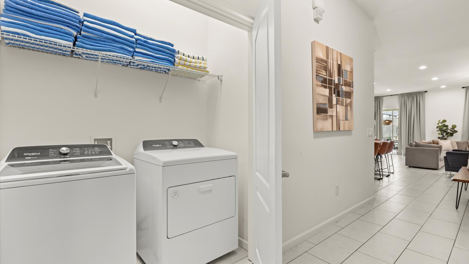 Laundry room with washer, dryer, and ample shelving.